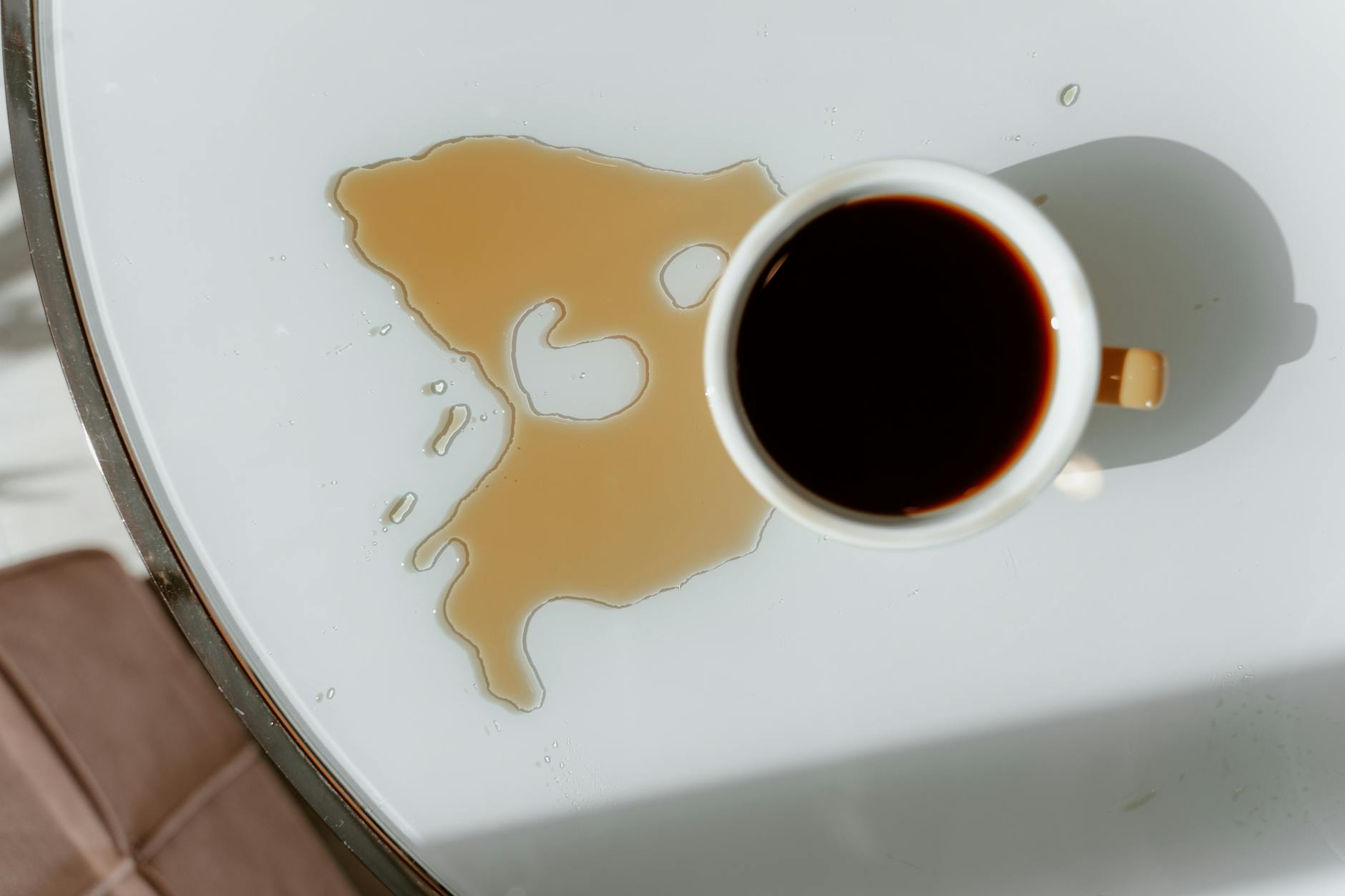 Overhead view of a coffee cup spill — showing the kind of stain that becomes much harder to remove once dried