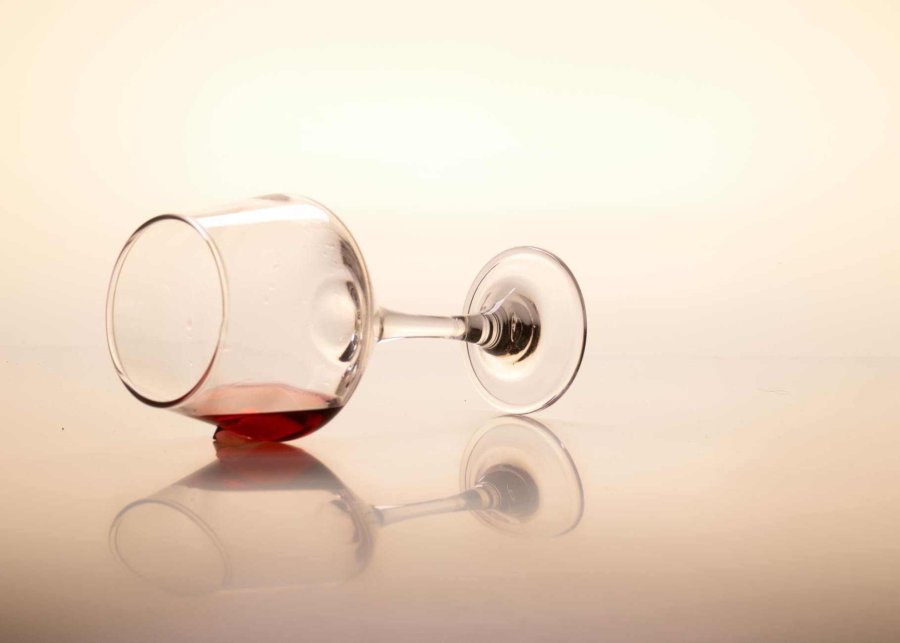 Tipped red wine glass creating a spill — illustrating one of the most notorious hard to remove carpet stains