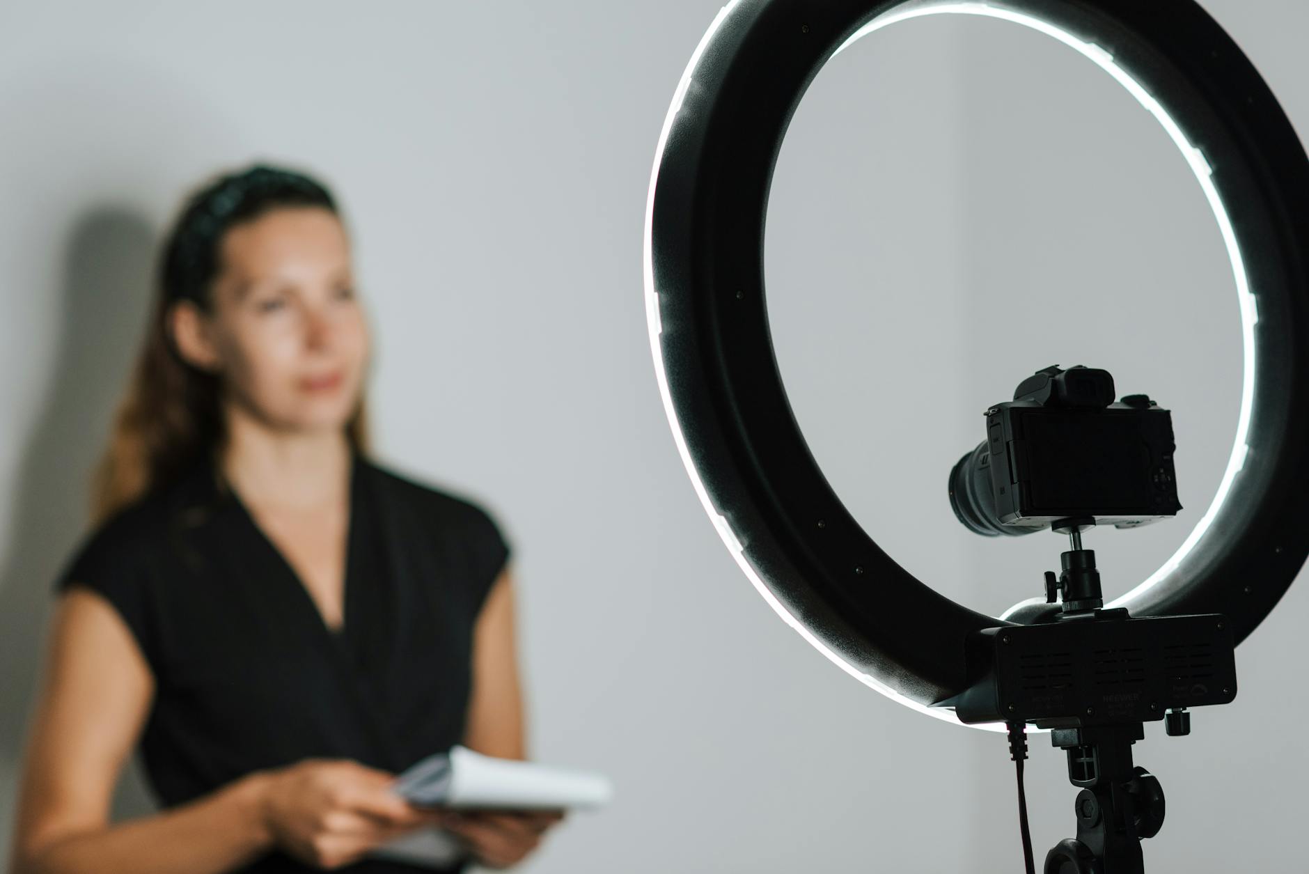 Female content creator recording video with LED ring light setup indoors