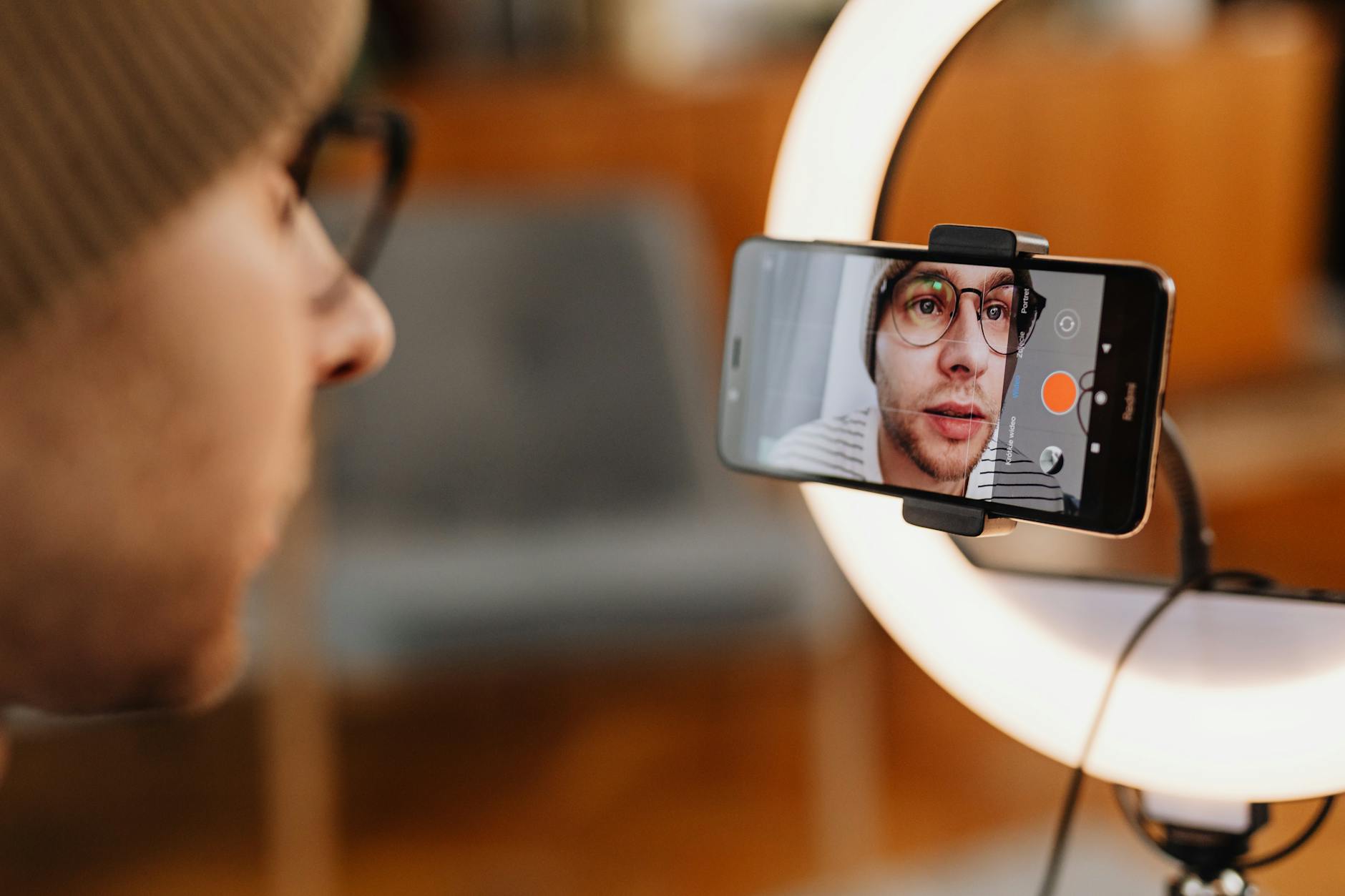 Content creator using ring light while filming selfie video on smartphone