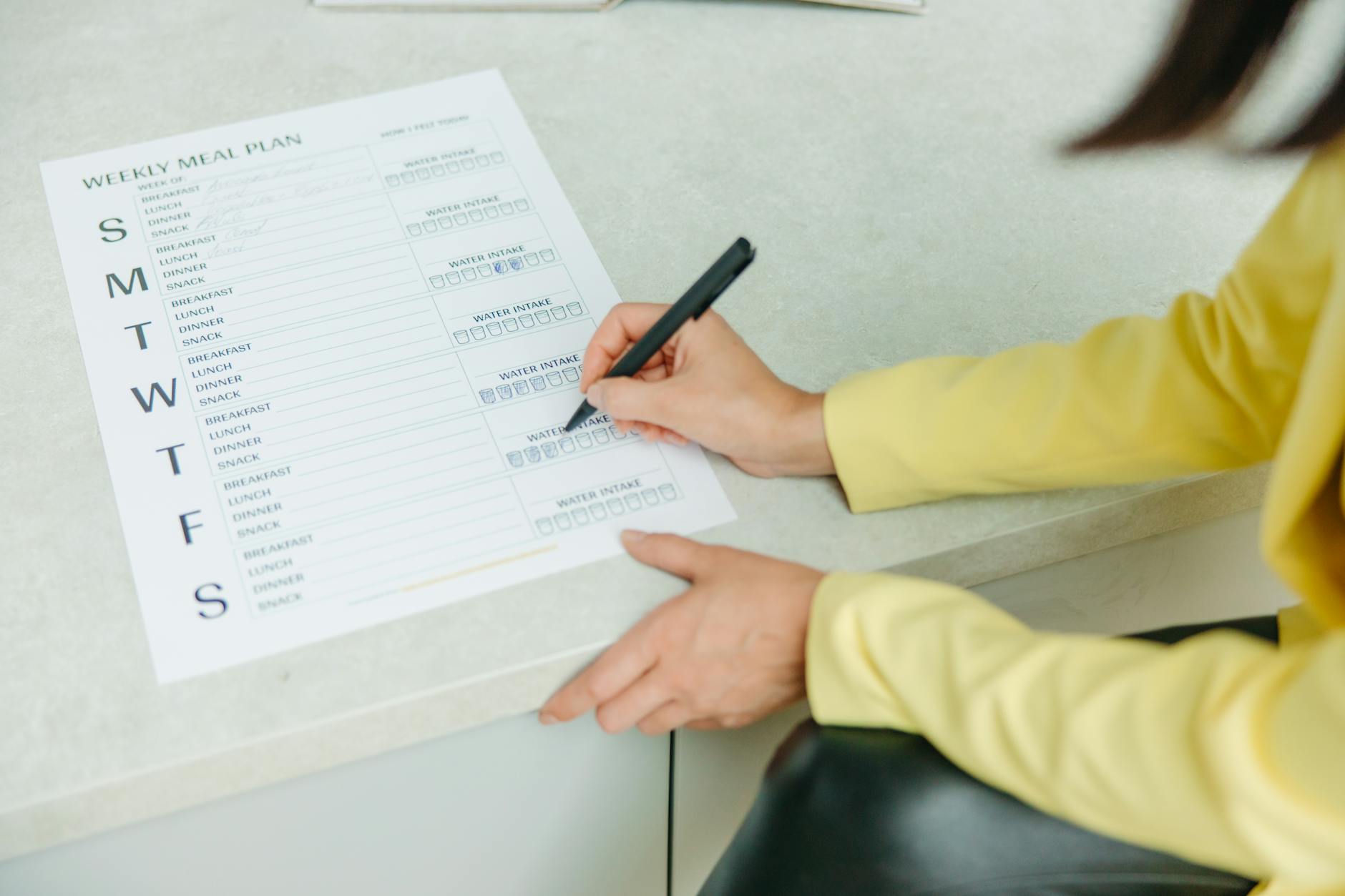 Woman writing out a weekly meal plan on a checklist to reduce food waste and stay organised