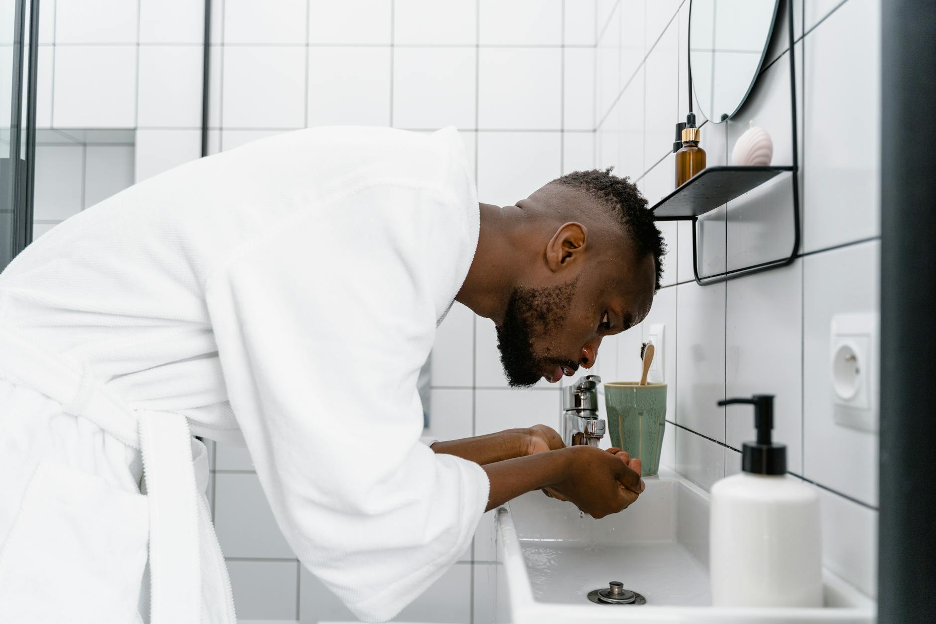 Man in bathrobe washing face in a modern bathroom — daily face washing routine