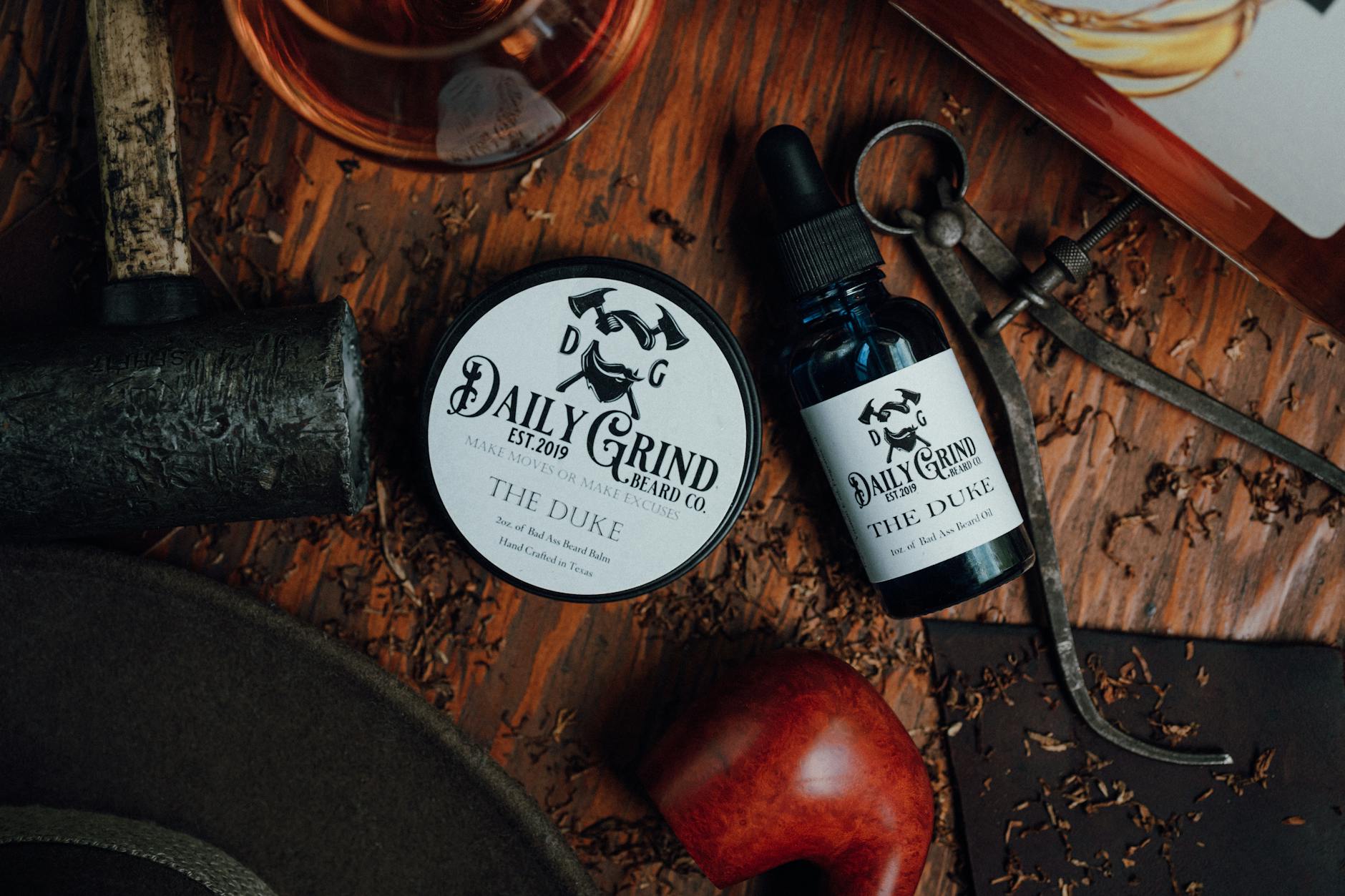 Men's grooming products including beard balm and oil arranged on wooden surface