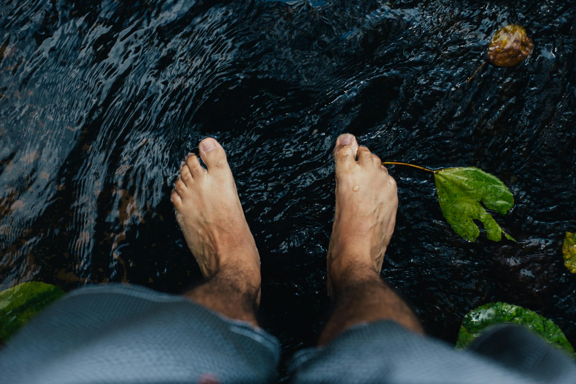 Close up of bare feet standing in flowing water, representing foot swelling and circulation