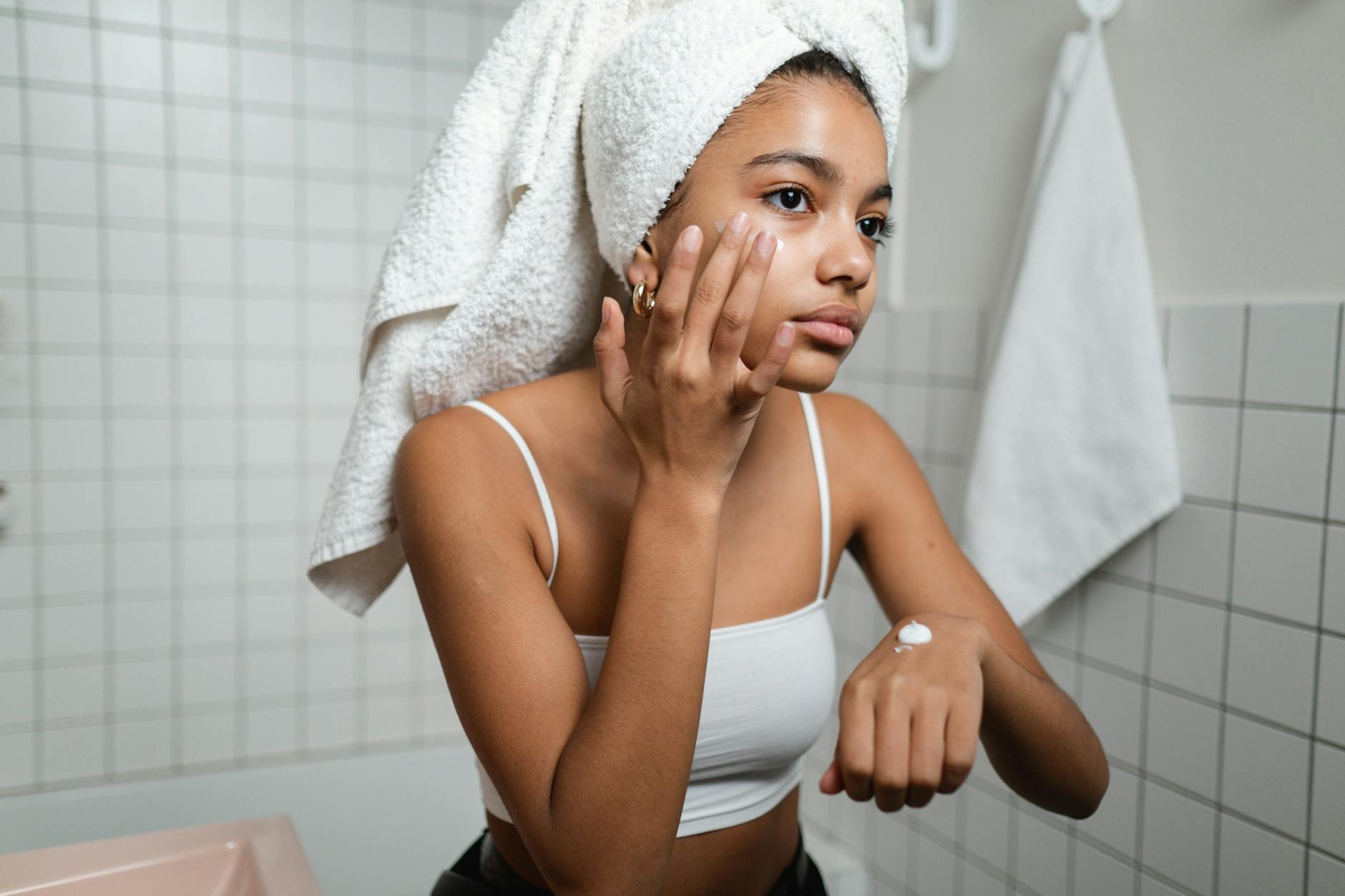 Morning Anti-Aging Skincare Routine Over 40 Woman applying skincare cream in bathroom mirror as part of her morning routine