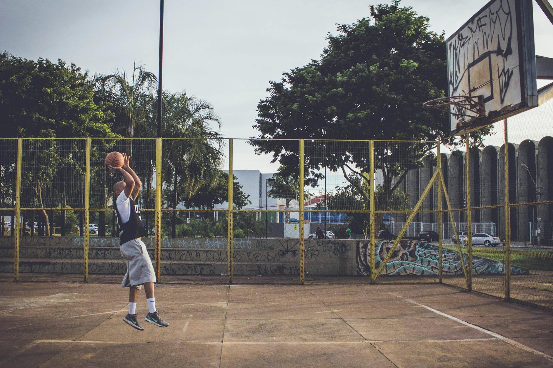 Basketball player jumping on an outdoor urban court wearing athletic shoes