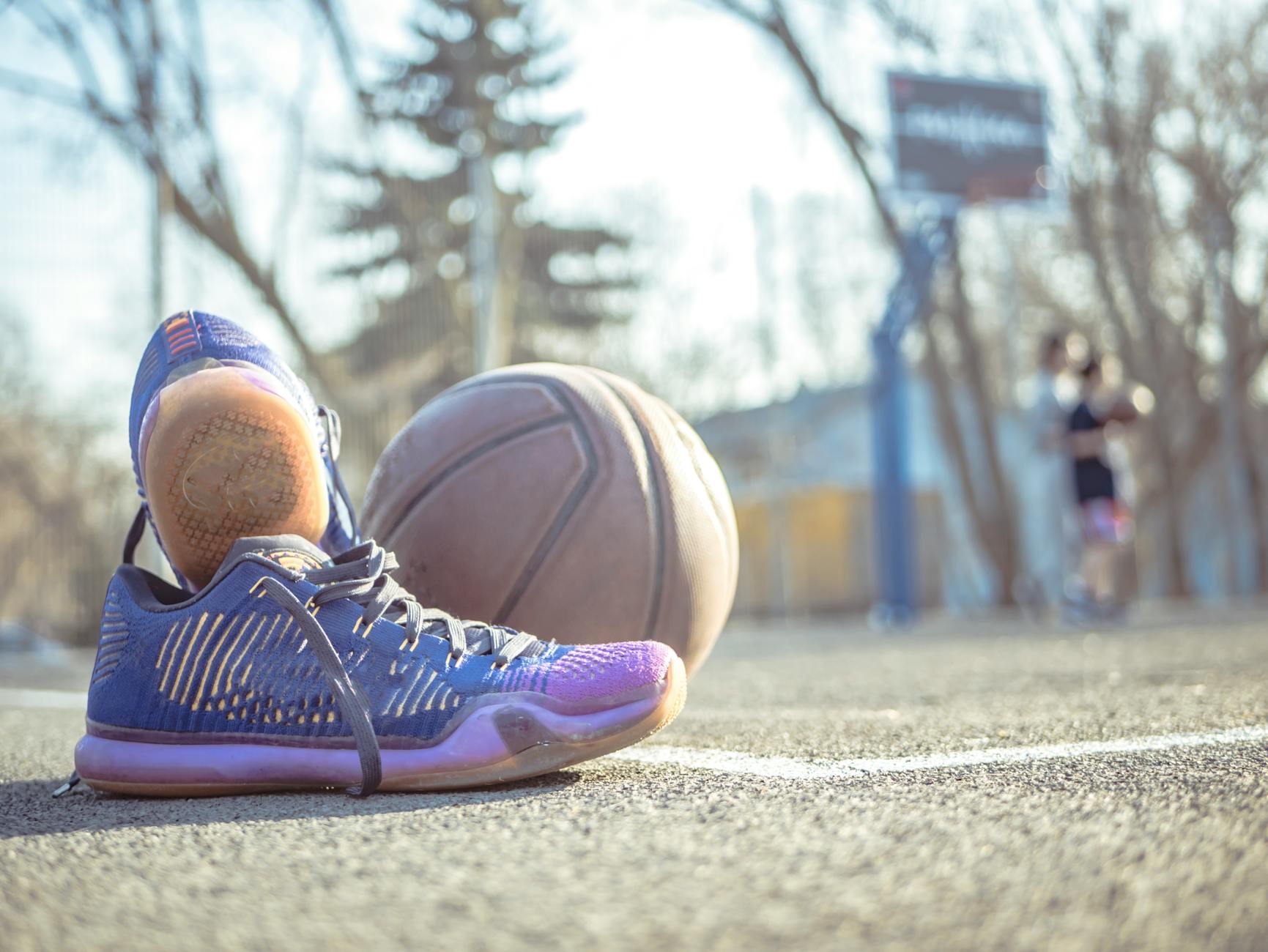 Sneakers placed next to a basketball on an outdoor court