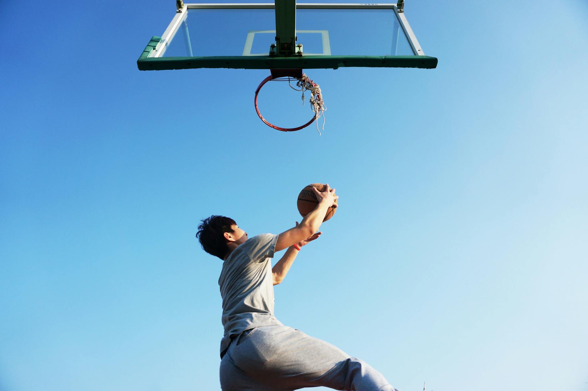Basketball player jumping explosively toward the hoop outdoors
