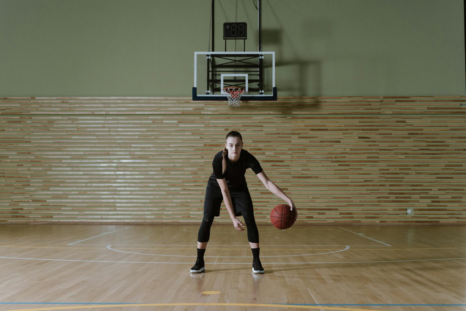 Woman focused on dribbling basketball in an indoor training setting