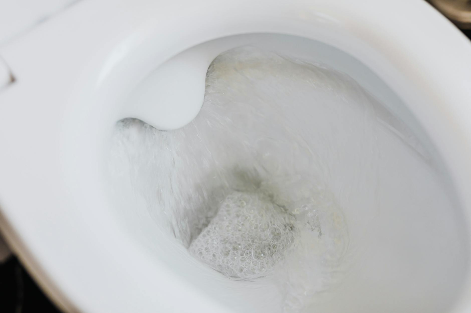 Clean toilet bowl with clear flushing water