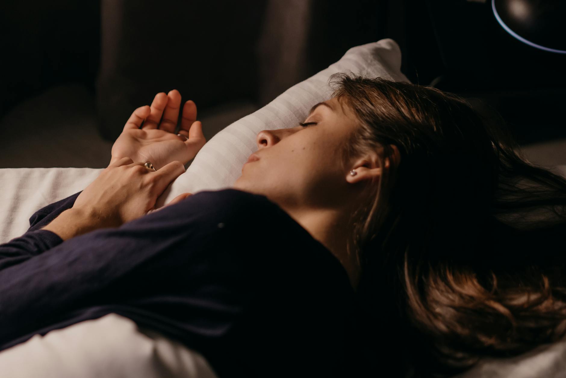 Dark, Cool Bedroom Environment for Better Sleep Woman sleeping comfortably in a softly lit bedroom at night