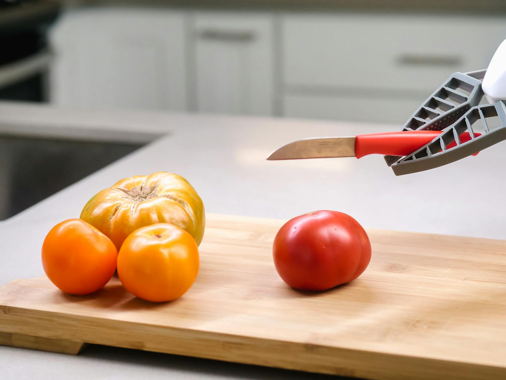 Fresh tomatoes and a knife on a cutting board in a modern kitchen