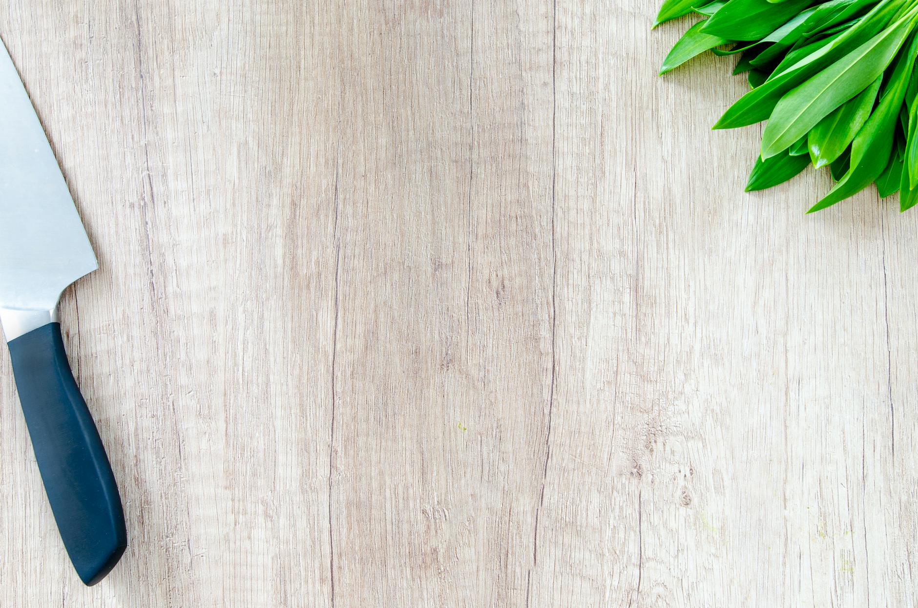 Wooden cutting board with fresh herbs and chef's knife on kitchen counter