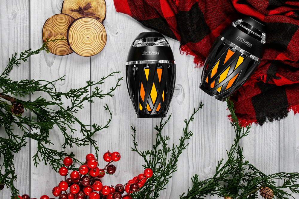 TikiTunes Ambient Lantern Speaker - Unique Outdoor Entertaining Gift Under $50 TikiTunes tiki-torch-style Bluetooth lanterns displayed among holiday gift wrapping and festive decor