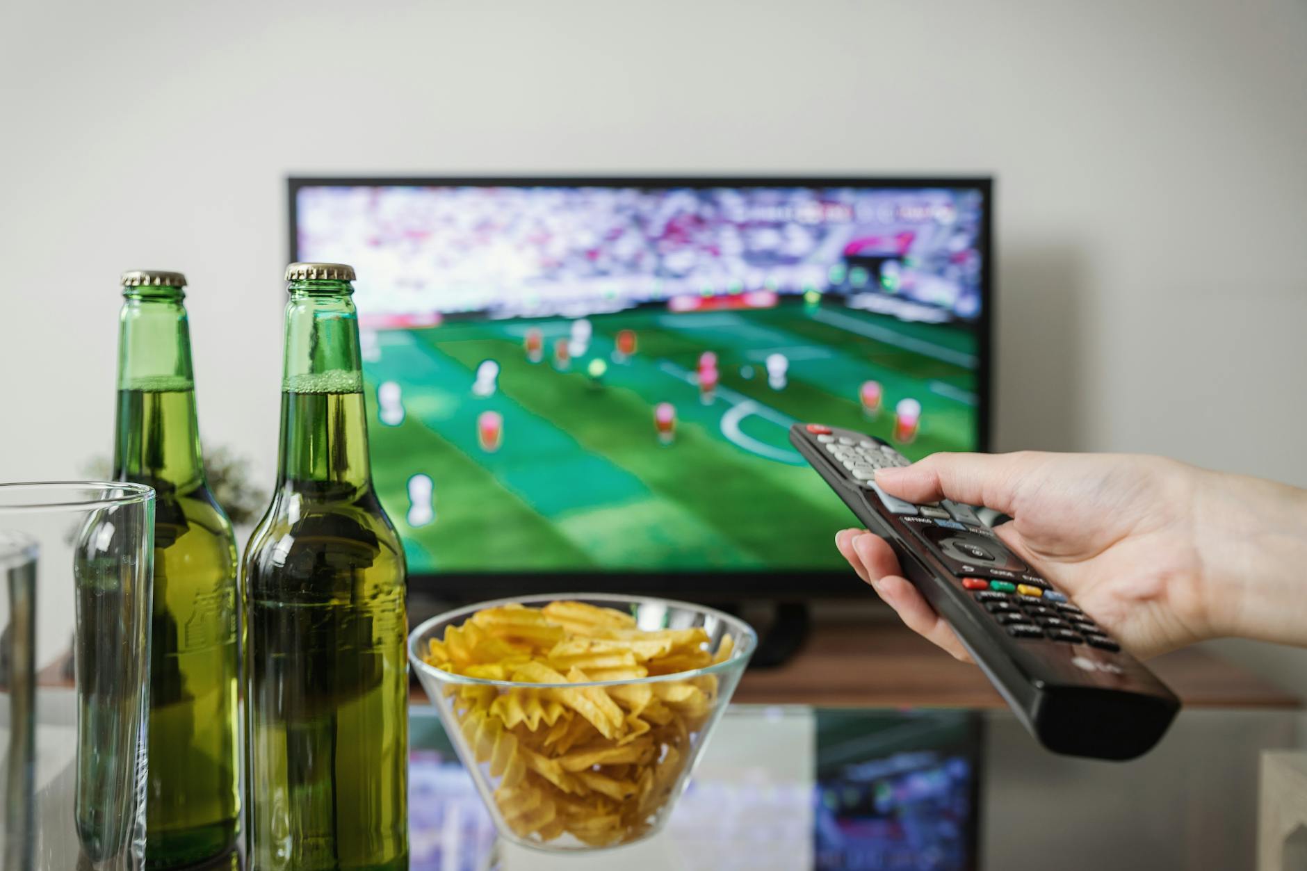 Person watching sports on TV with snacks and remote — classic NBA game day setup