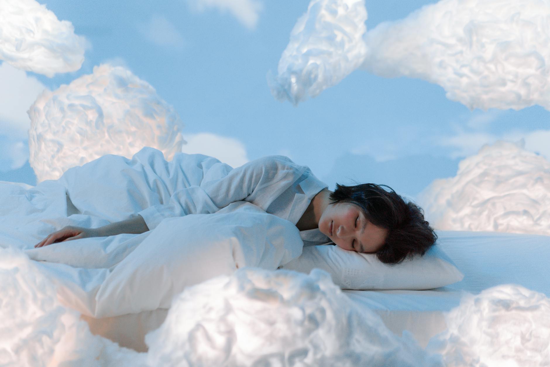 Woman in a peaceful, dreamy sleep surrounded by soft clouds — representing the goal of restful sleep through breathing exercises