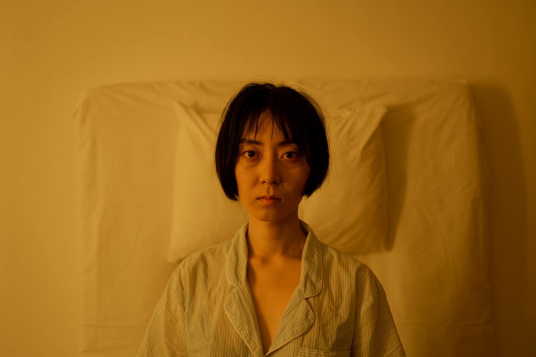 Woman sitting up in bed looking stressed and unable to sleep due to cortisol and nervous system activation