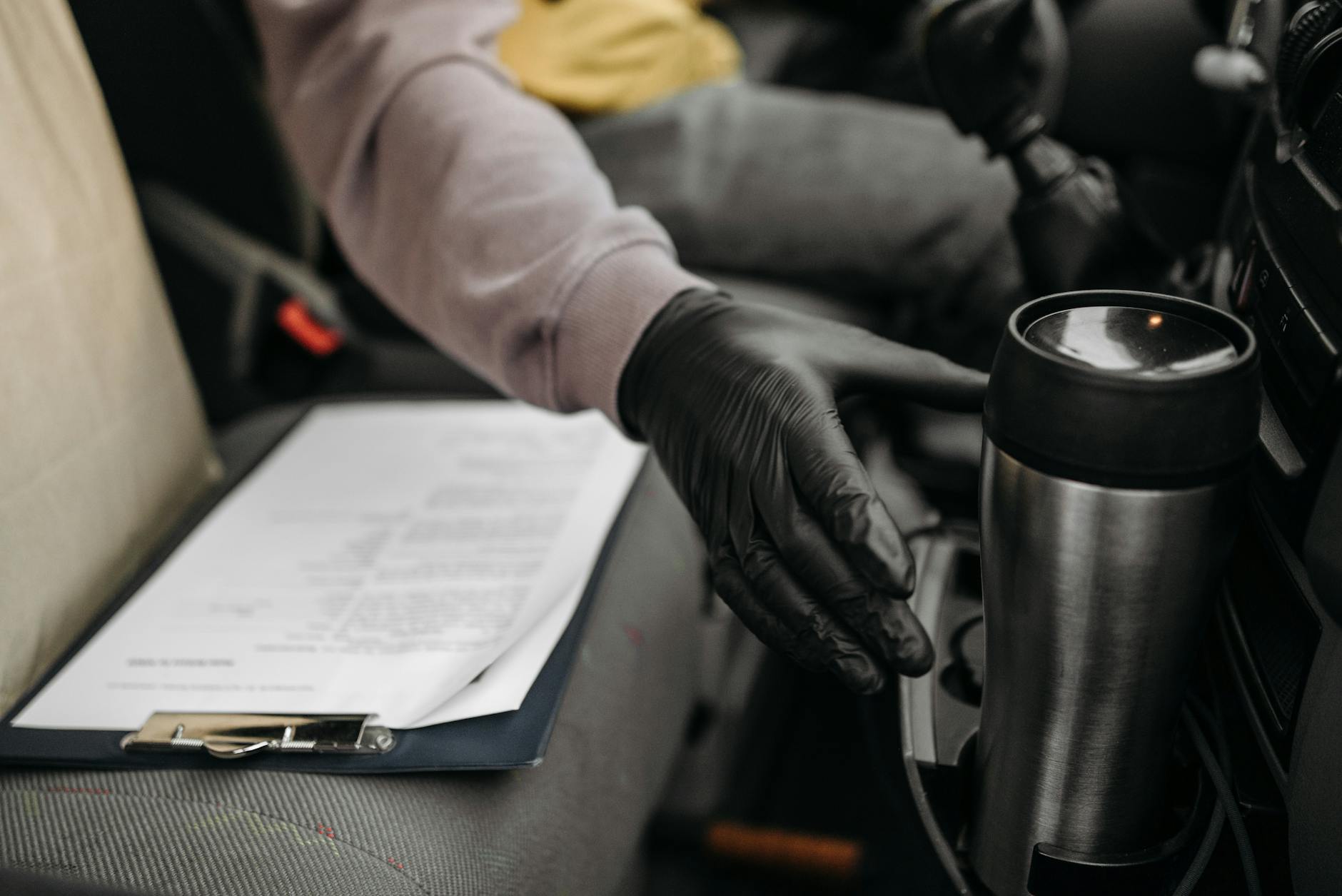 Organized car interior with driver essentials within reach — thermos, clipboard and gear