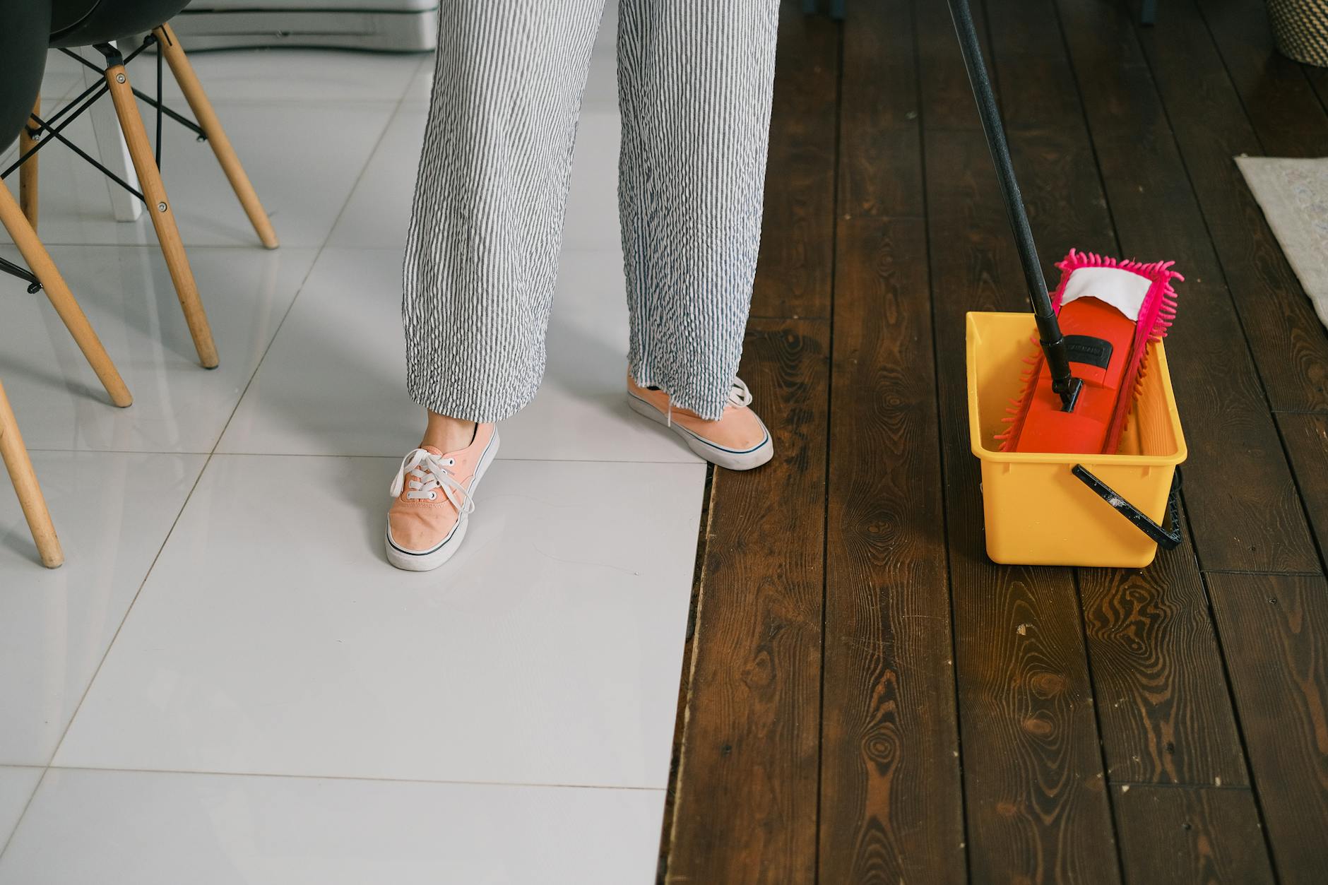 A person mopping a wooden floor, showing proper floor cleaning technique