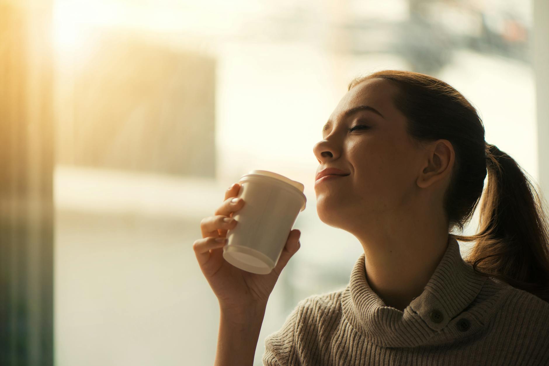 Woman enjoying her morning coffee by the window — understanding coffee staining habits
