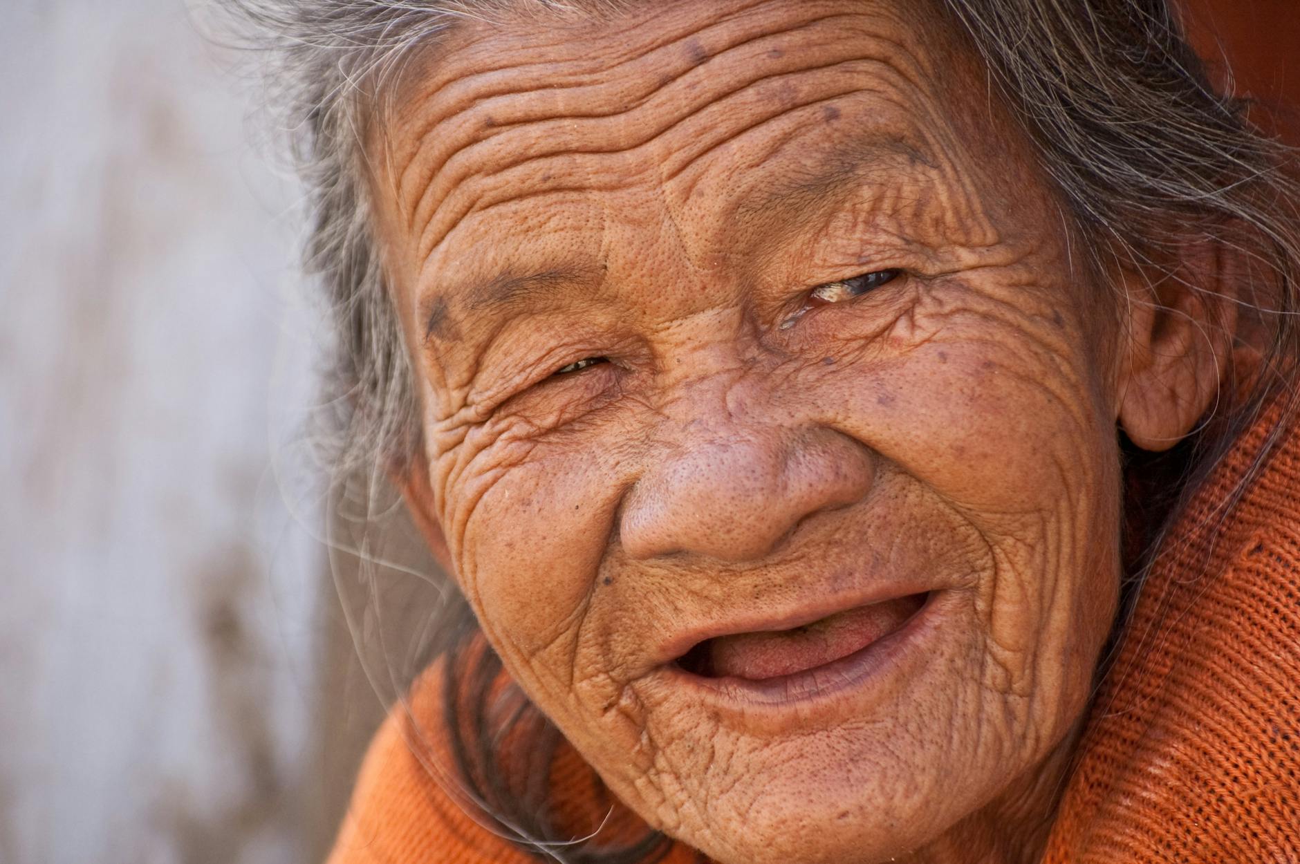 Natural crow's feet wrinkles around the eye area Elderly woman smiling with natural crow's feet wrinkles around her eyes