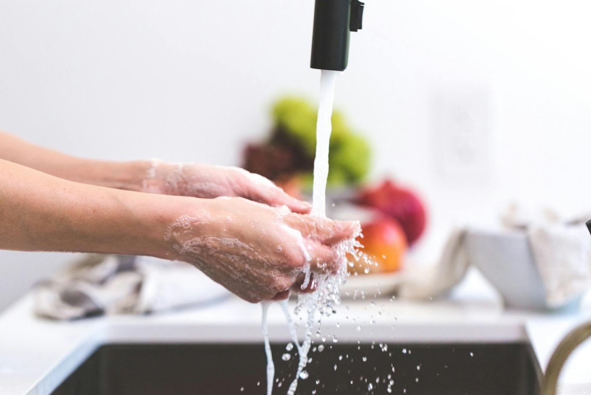 Hands being washed under running water before handling food — a key step in kitchen hygiene