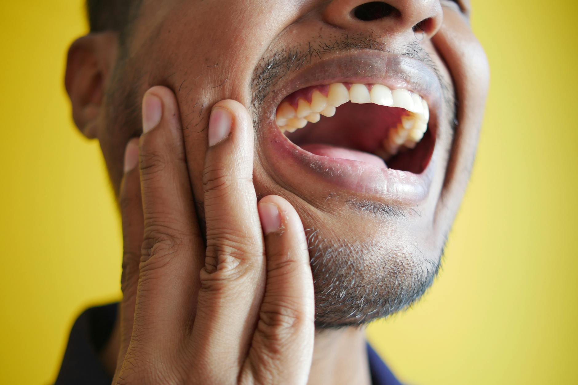 Tooth Pain and Jaw Discomfort - Early Signs of Tooth Decay Man holding jaw in discomfort, a common response to tooth pain from advancing decay
