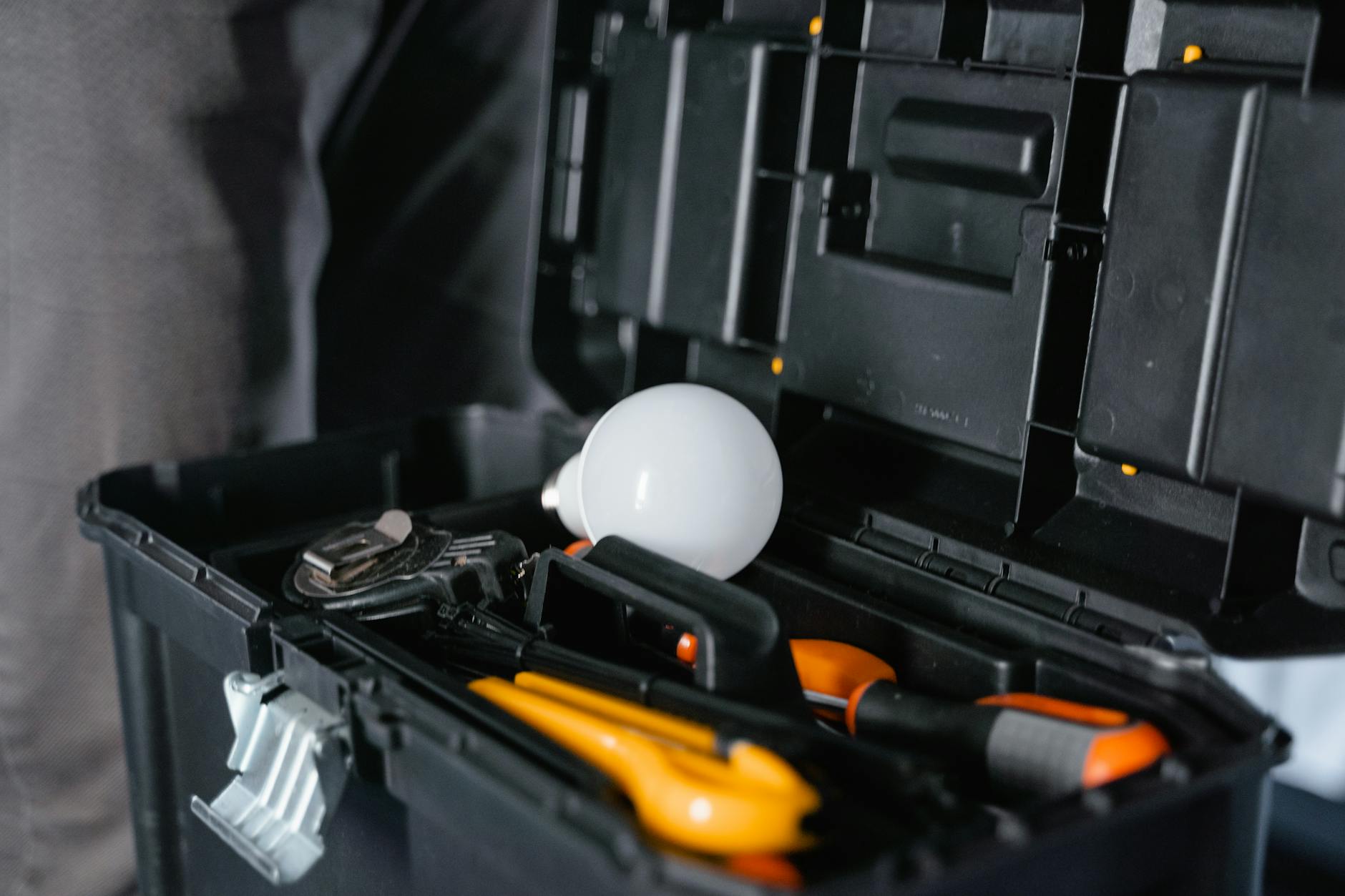 Open toolbox with various tools and a light bulb for home repair and maintenance