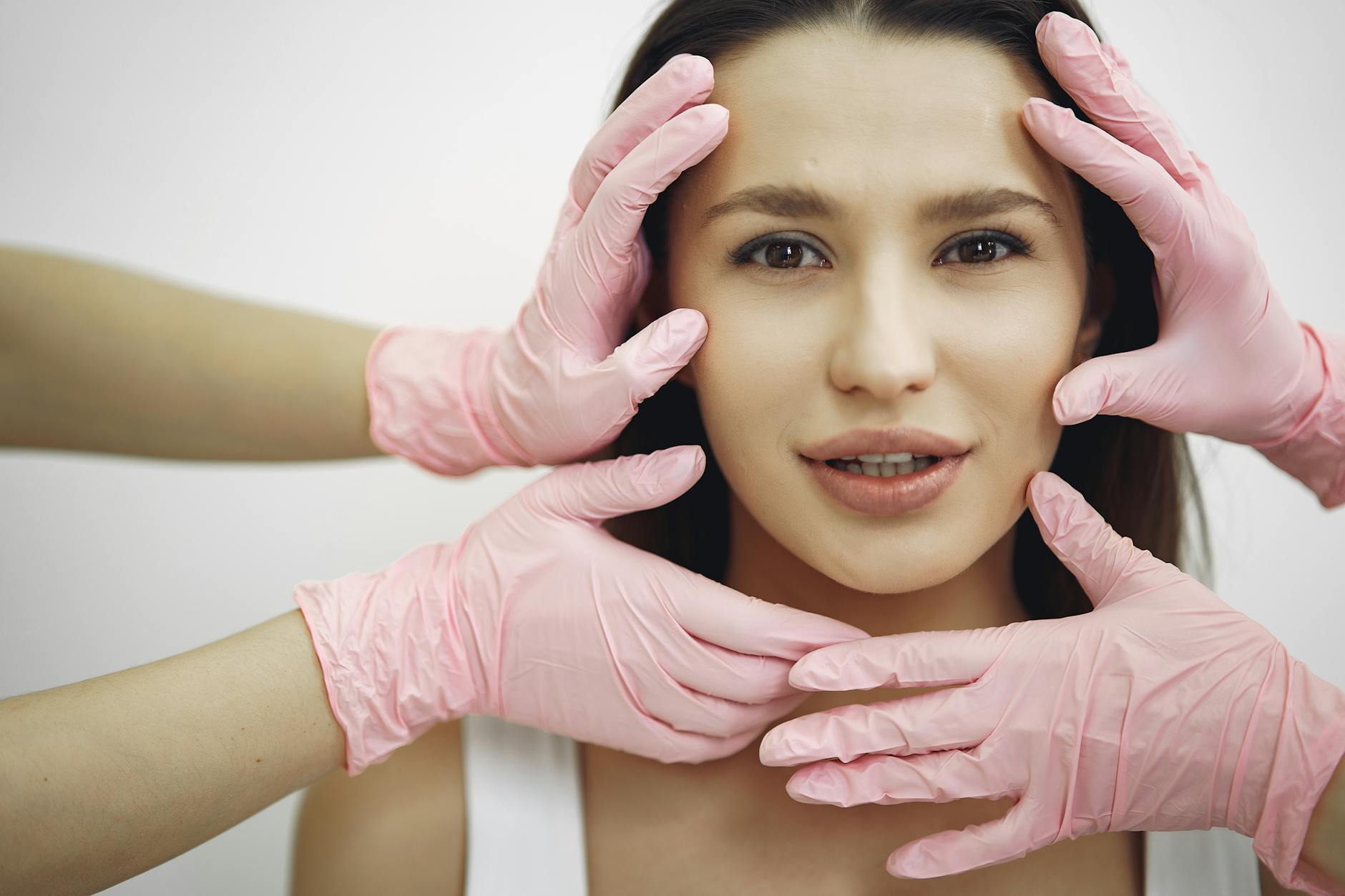 Woman receiving a professional facial treatment in a clinical setting with gloved hands
