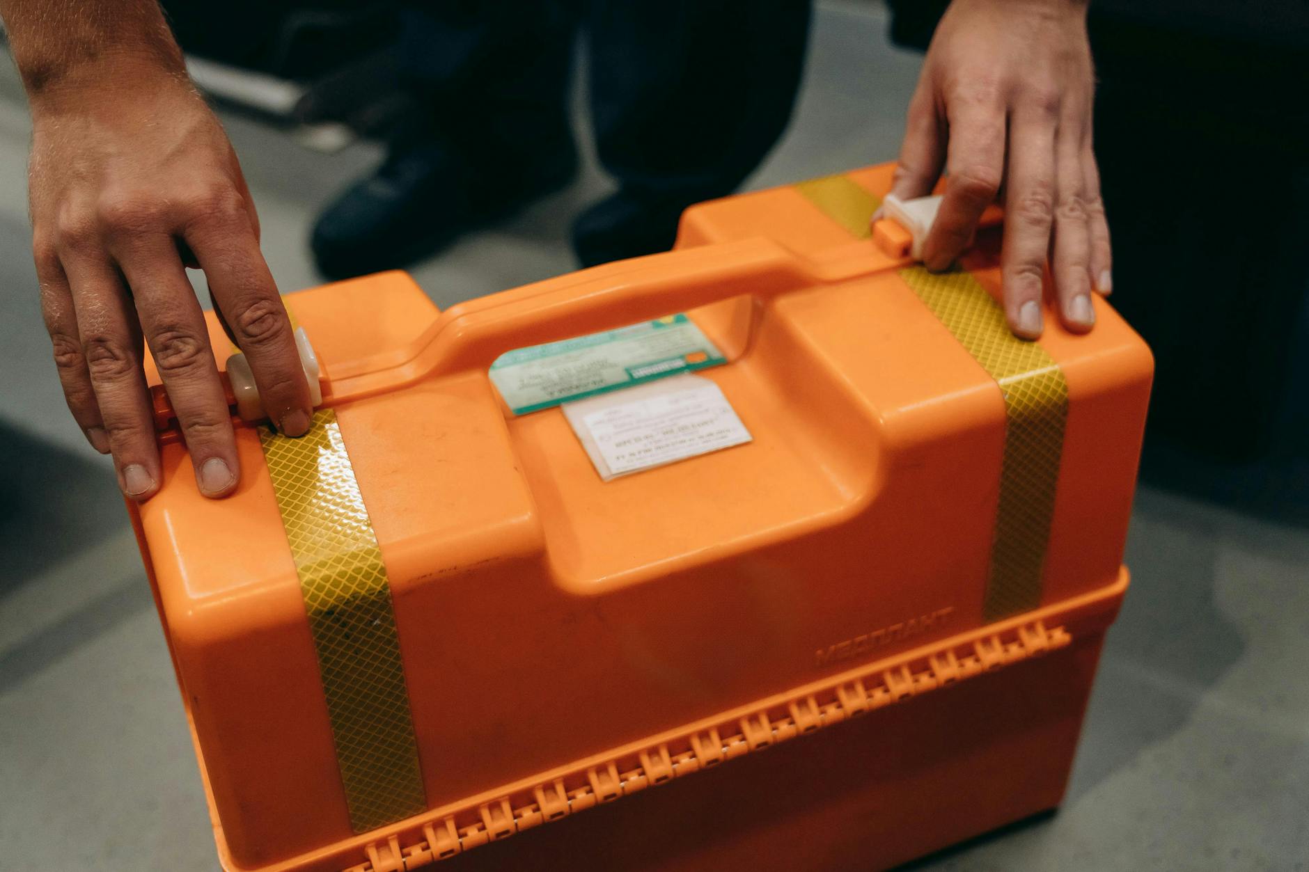 Emergency Medical Kit — Emergency Preparedness Basics 2026 Hands holding an orange emergency medical kit — having physical supplies is one component of emergency preparedness