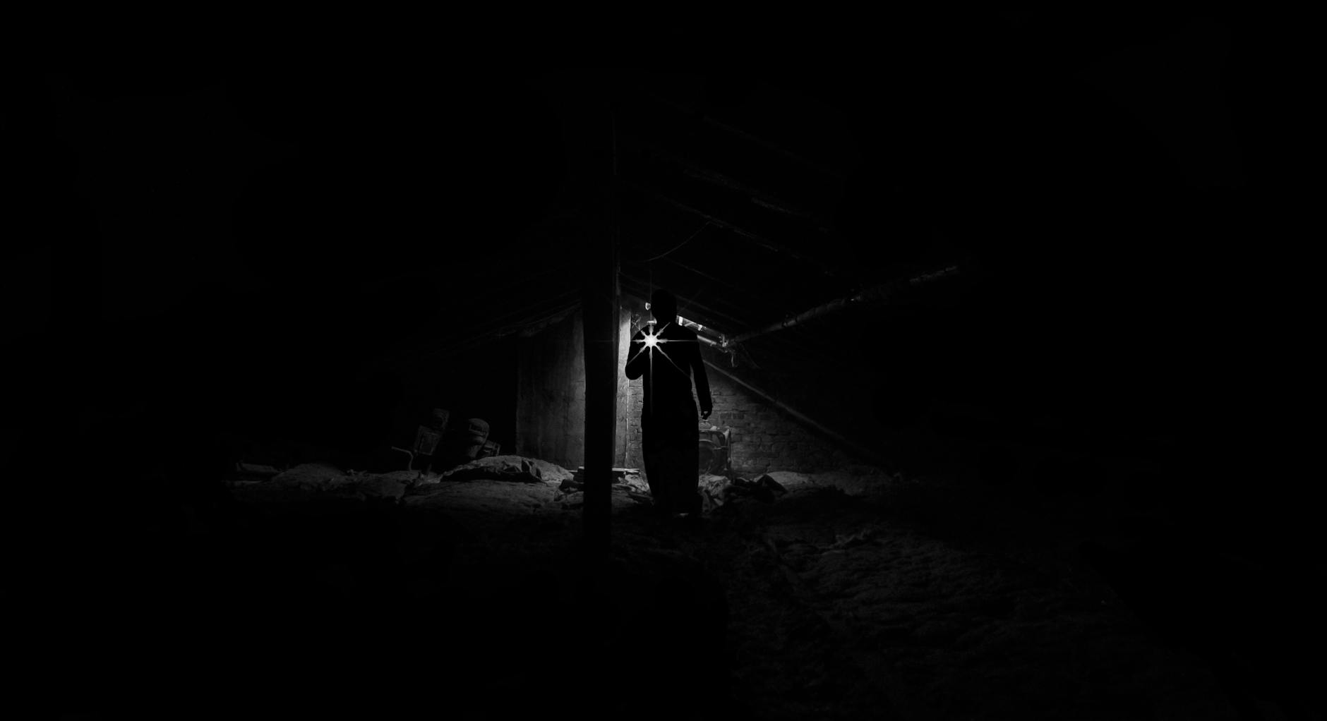 Person using a flashlight in a dark room during a power outage