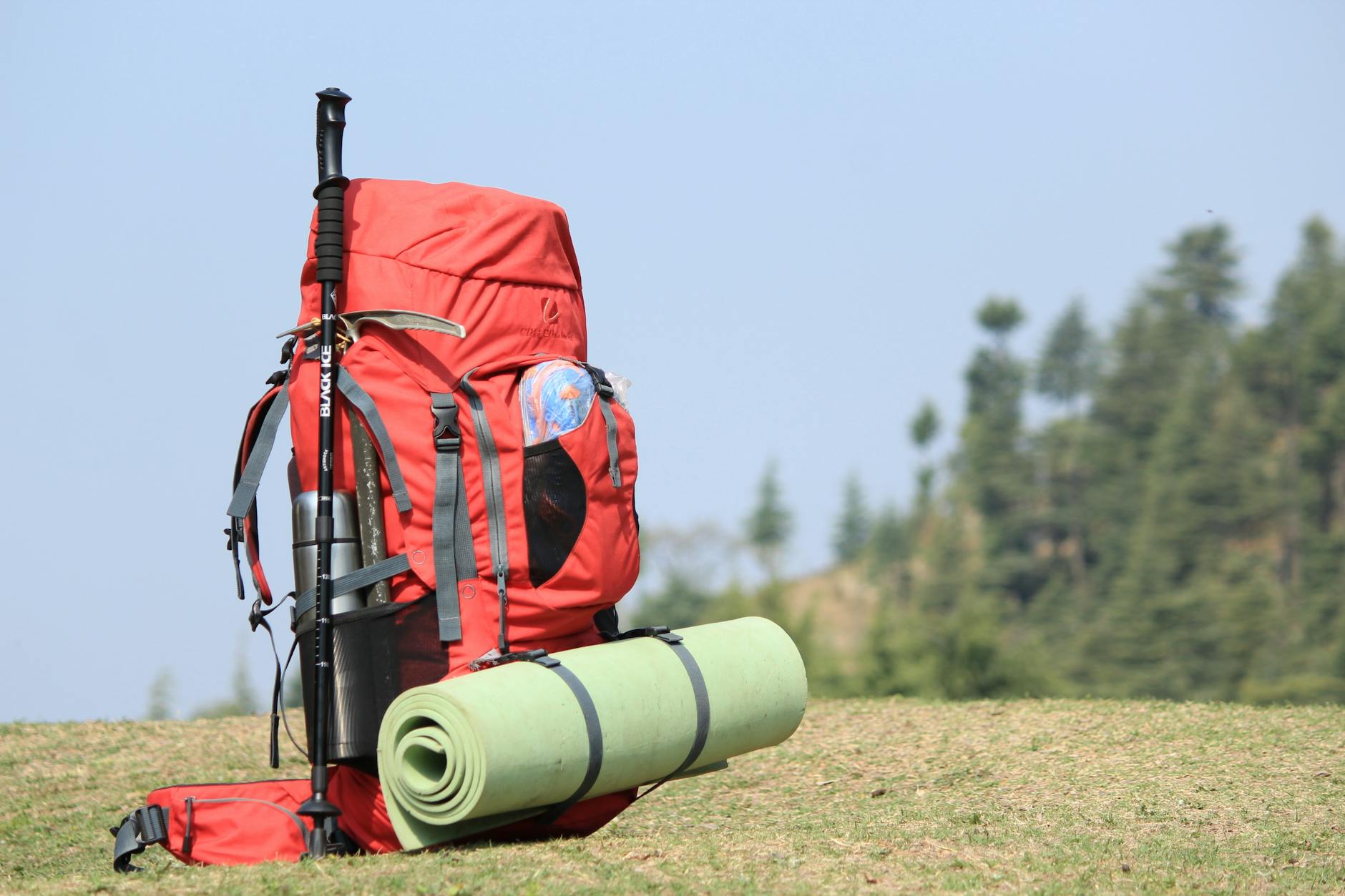 Backpack and Trekking Poles Ready for a Day Hike Red backpack and hiking poles on grassy field ready for a trail hike