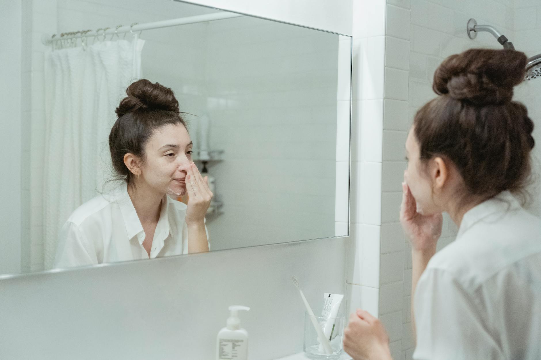 Morning Eye Care Routine for Women Over 40 Woman applying skincare product in front of bathroom mirror as part of her morning eye care routine