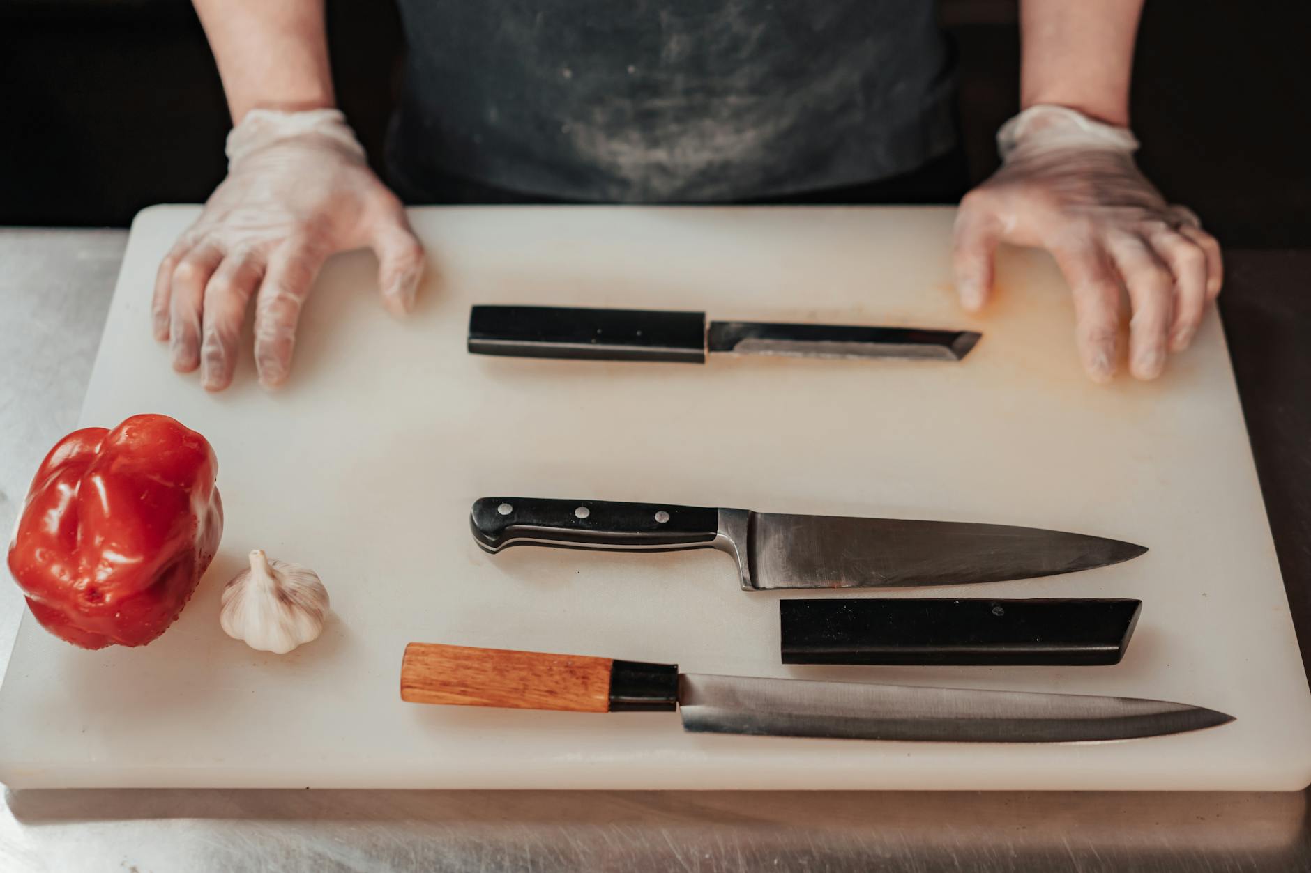 Gloved hands preparing to chop vegetables on a cutting board — demonstrating how to prevent cross contamination in the kitchen