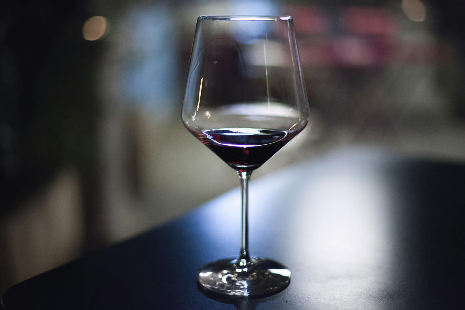 A glass of red wine on a dark table — red wine's tannins and anthocyanins make it one of the worst drinks for tooth staining