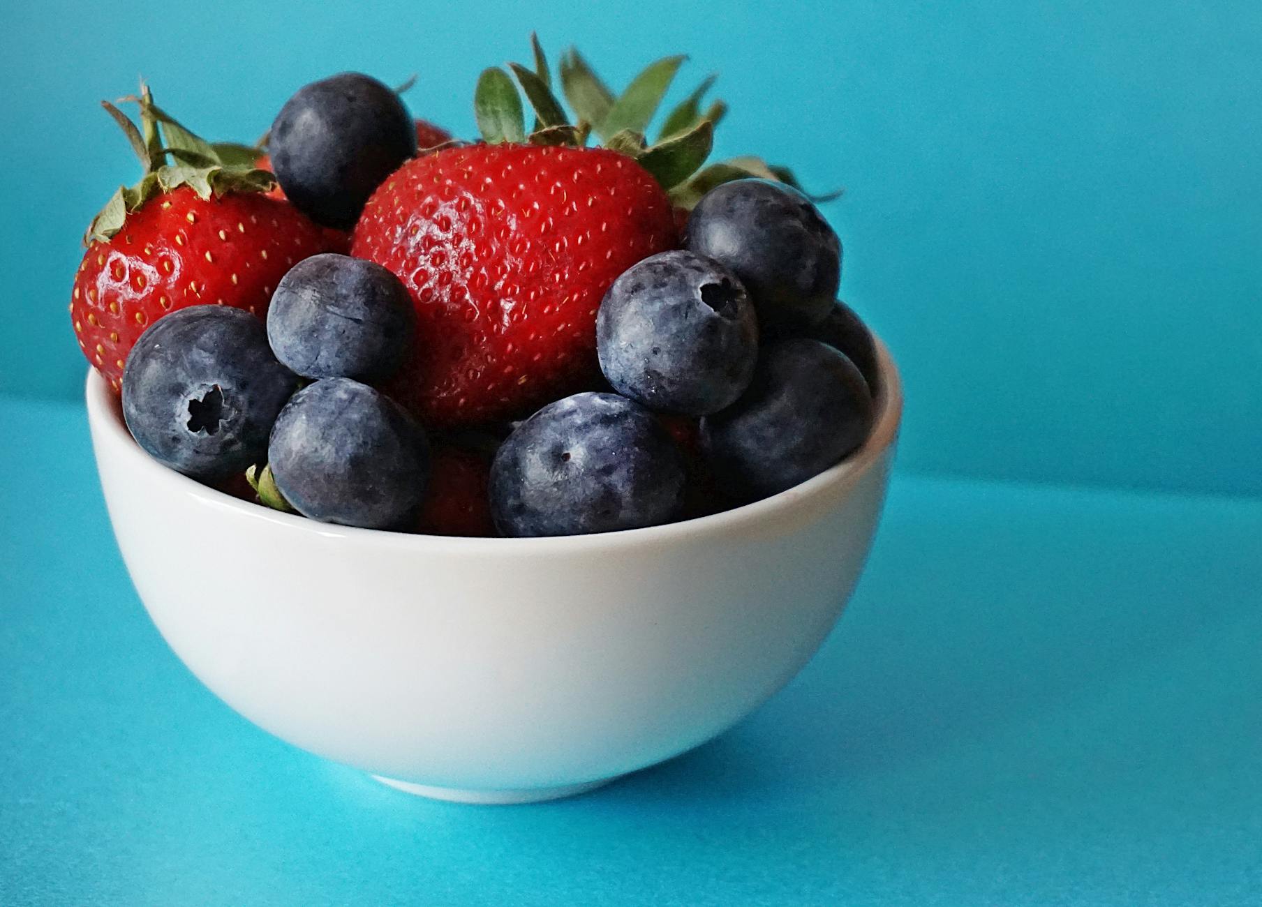 Bowl of fresh strawberries and blueberries — colorful berries are among the top foods that stain teeth