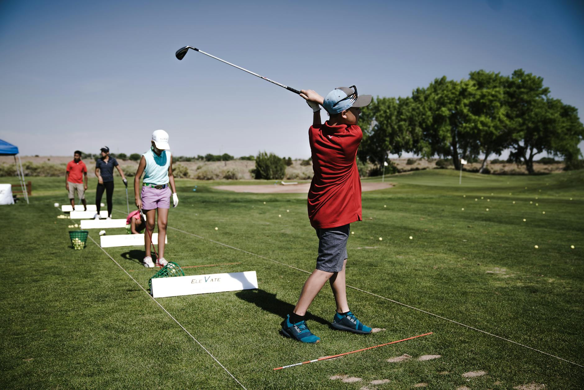 Youth golfers practicing swing technique at a driving range — flexibility is key to a repeatable swing