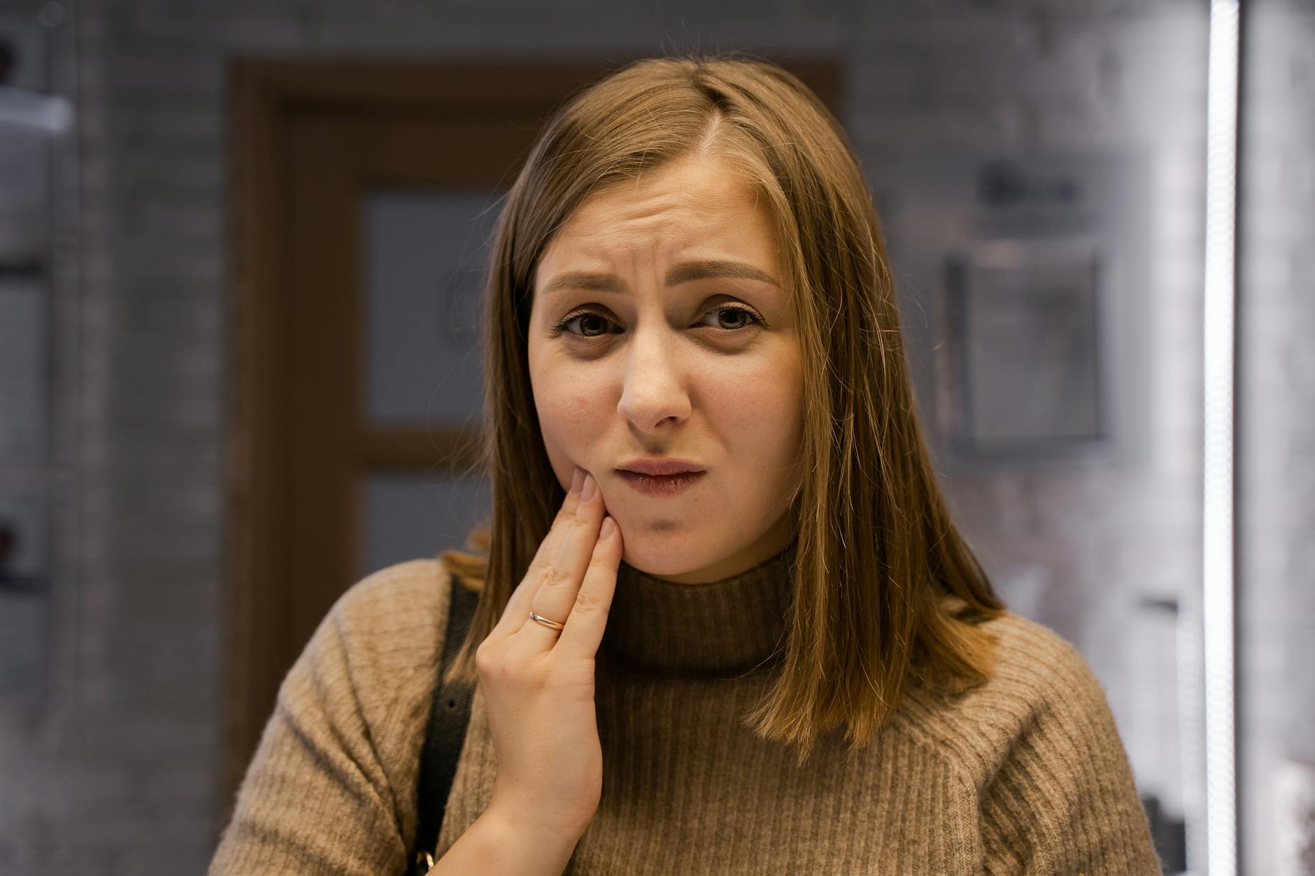 Dental Pain and Periodontitis Discomfort Woman experiencing dental pain and gum discomfort holding her jaw