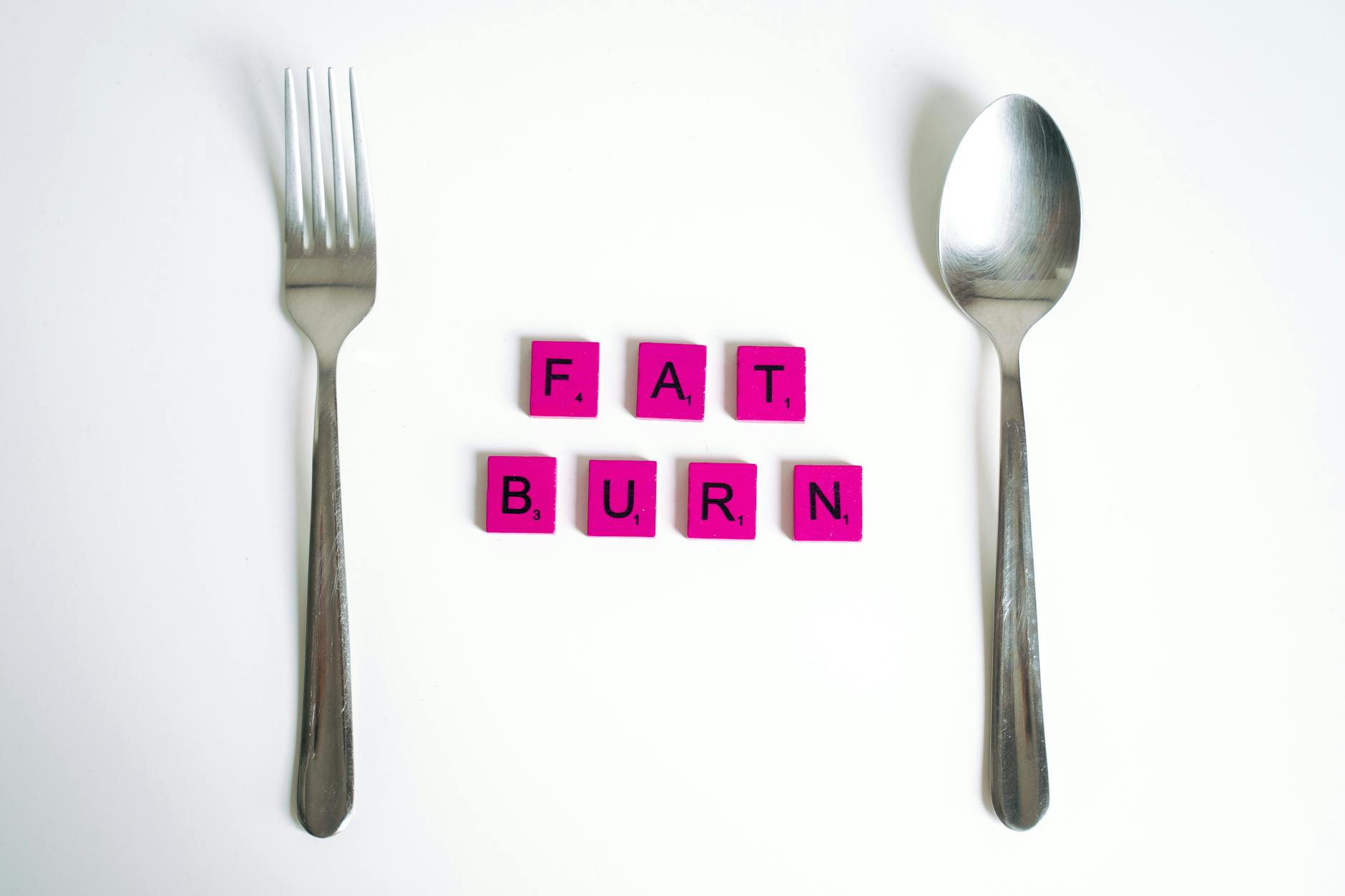 Fat Burning Metabolism Concept Fat burn metabolism concept with Scrabble tiles between fork and spoon