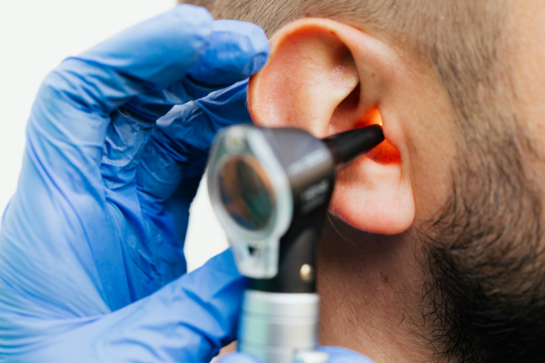Doctor examining a patient's ear with an otoscope during a hearing health checkup