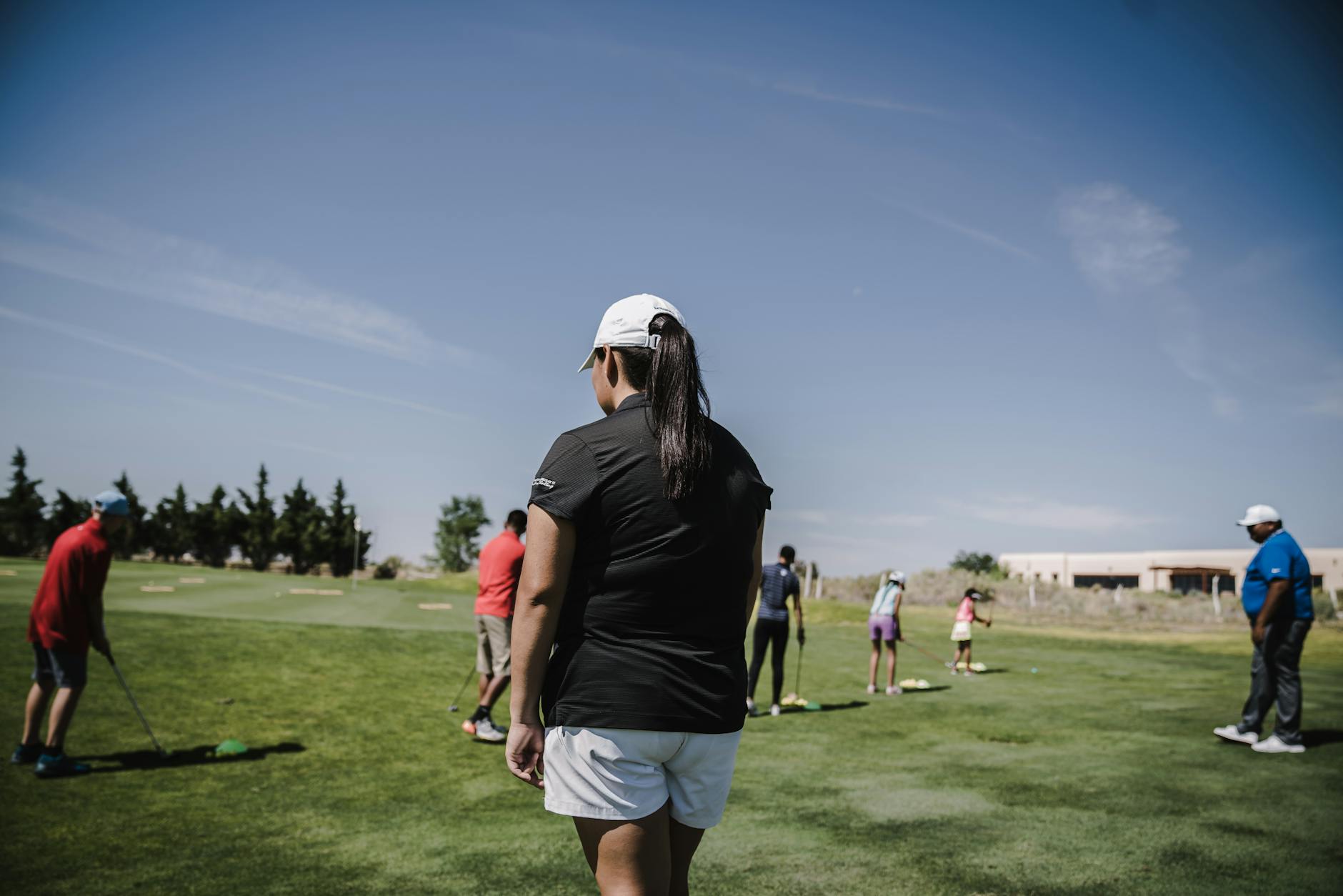 Group of golfers receiving instruction on a sunny golf course