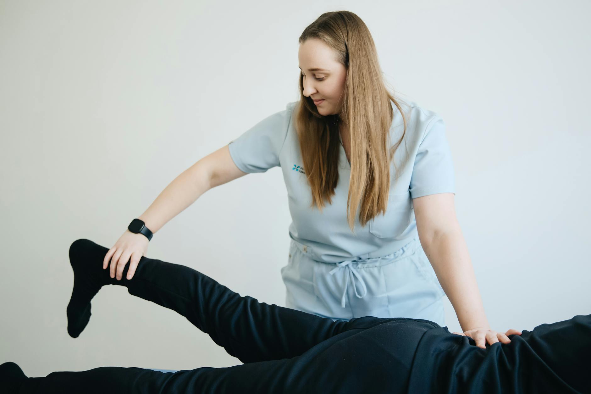 EMS Therapy for Leg Rehabilitation Female physiotherapist assisting a patient during a leg therapy session in a clinical environment