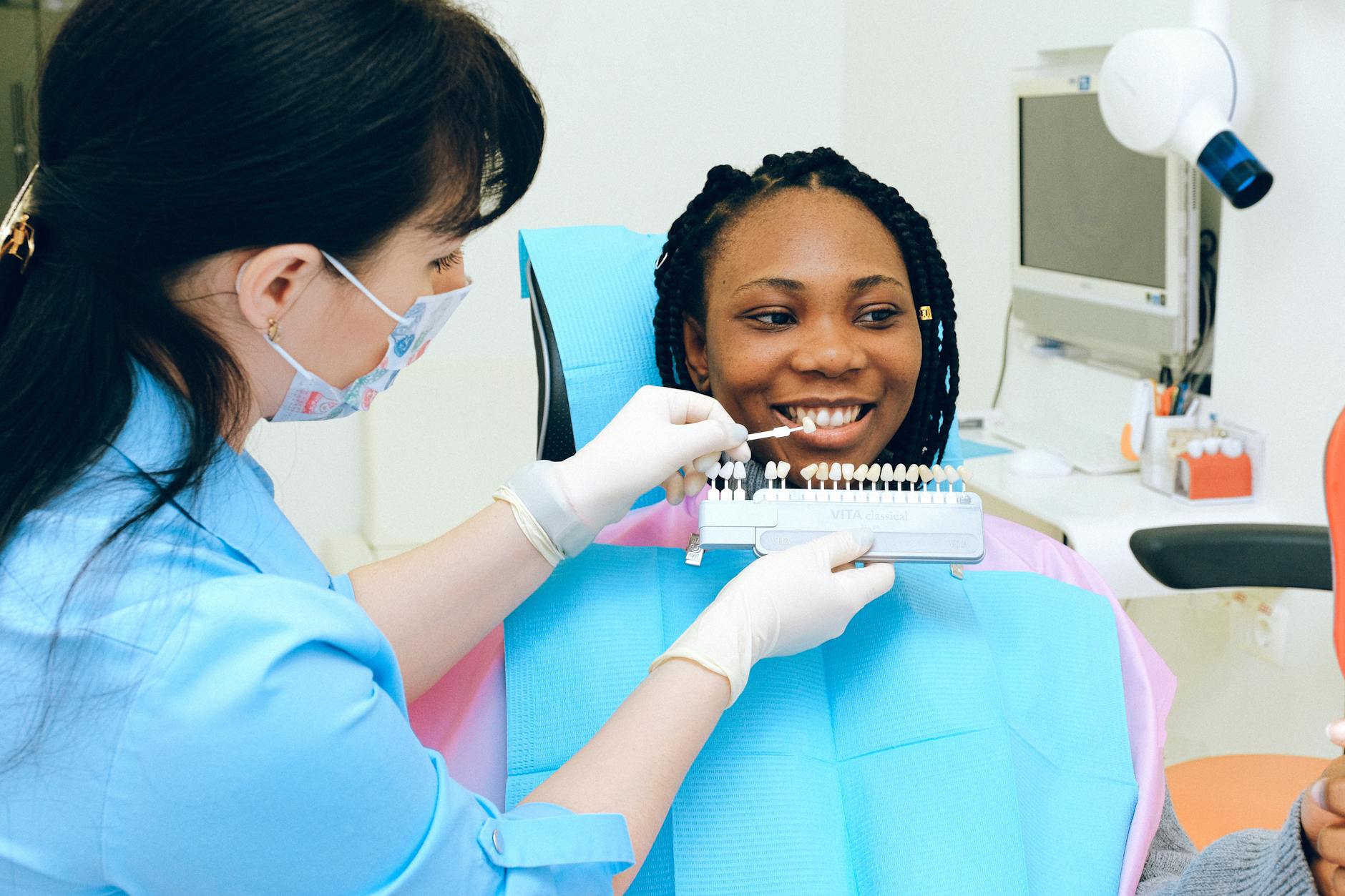 Dentist consulting with patient using teeth color shade samples in a dental clinic