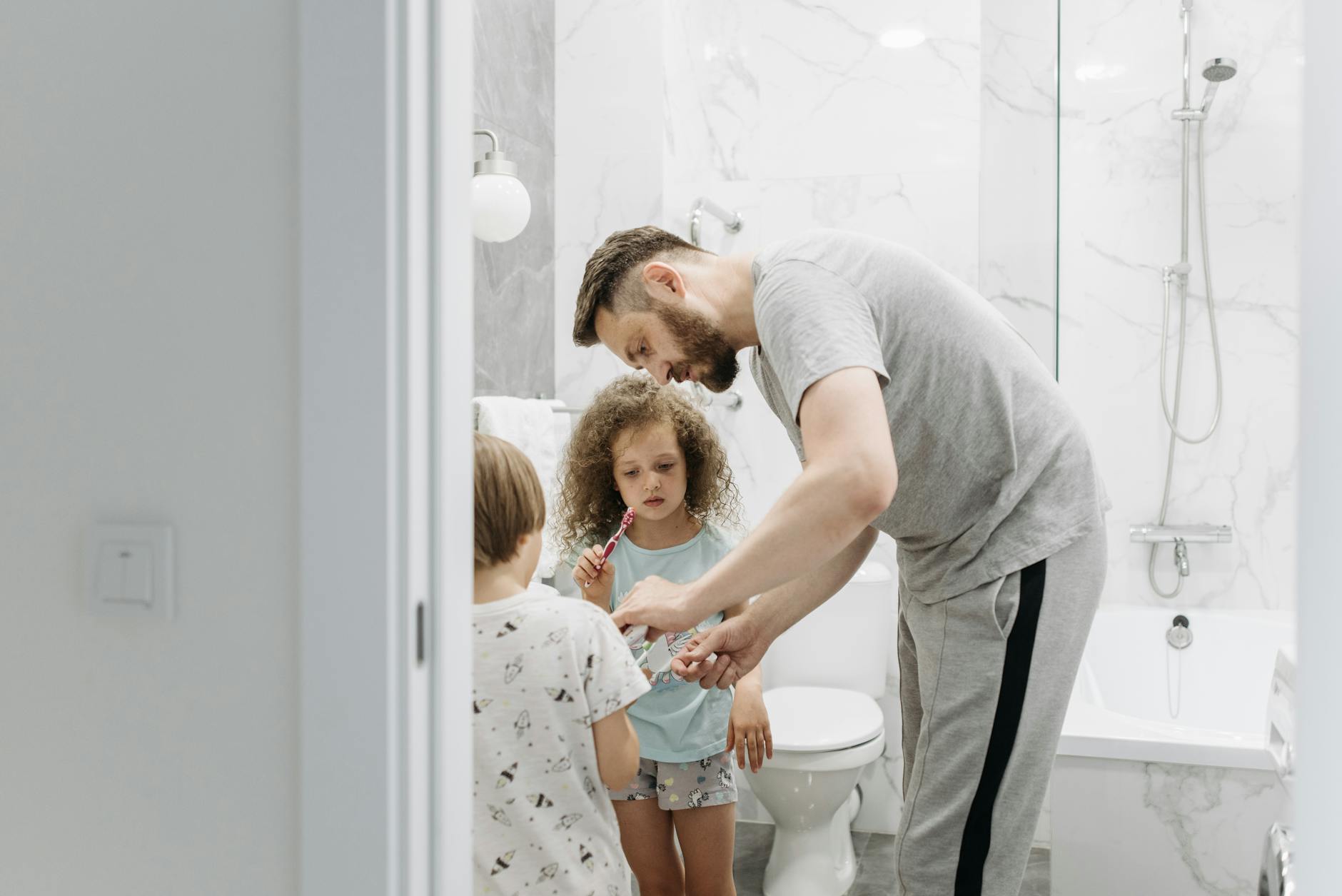 Father and children in a bathroom during their daily hygiene routine, illustrating high-traffic household bathroom use