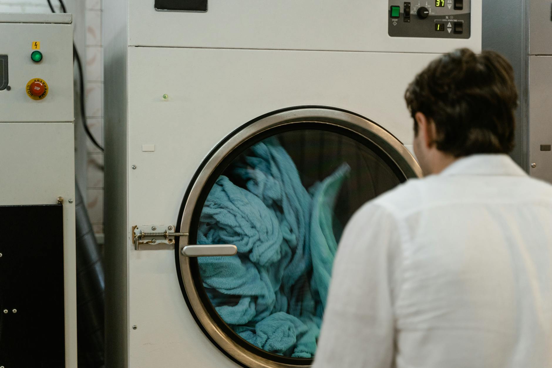Person using a washing machine to launder bathroom textiles and bath mats
