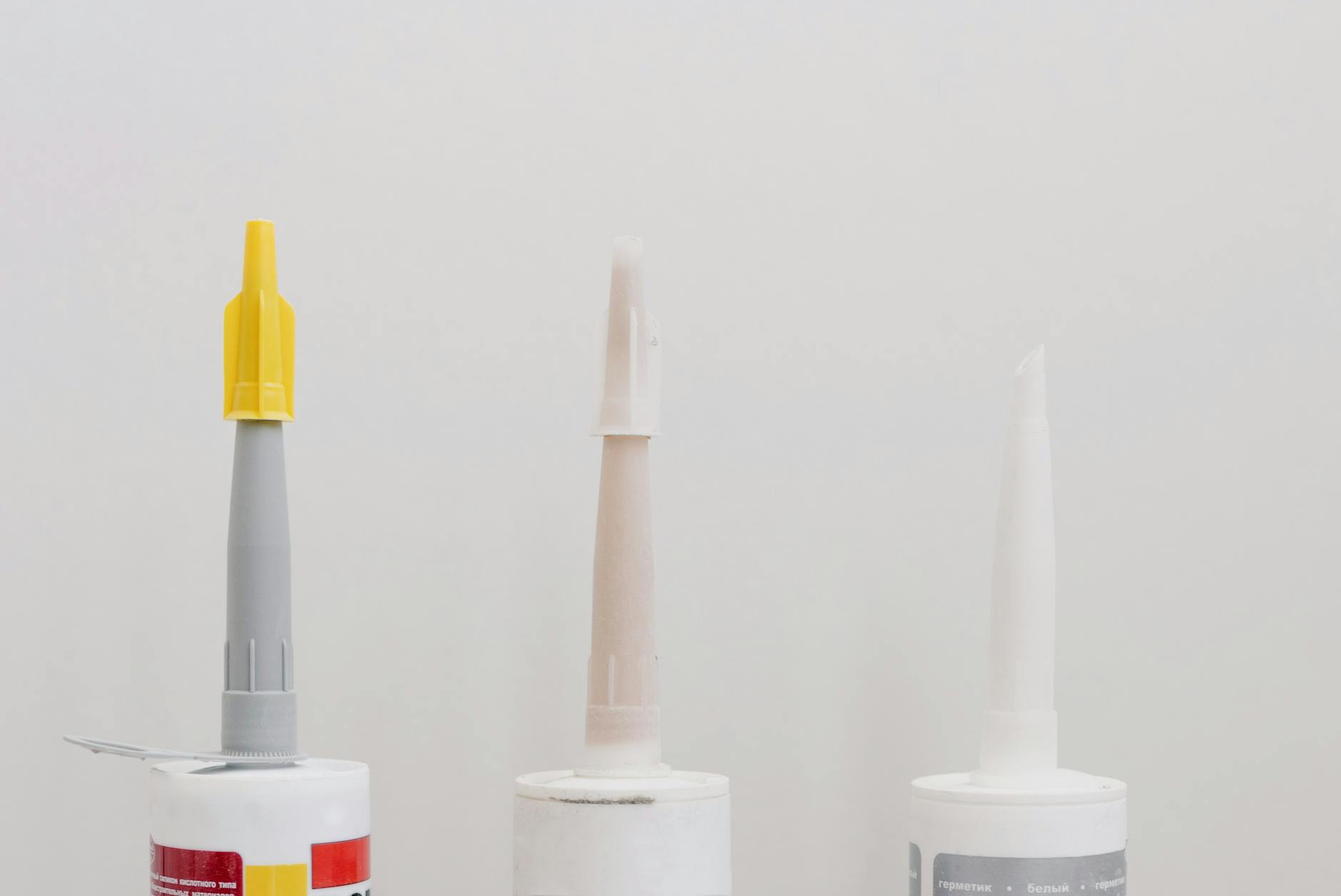 Various adhesive and glue tubes laid out for repair work, including different types suitable for plastic bonding
