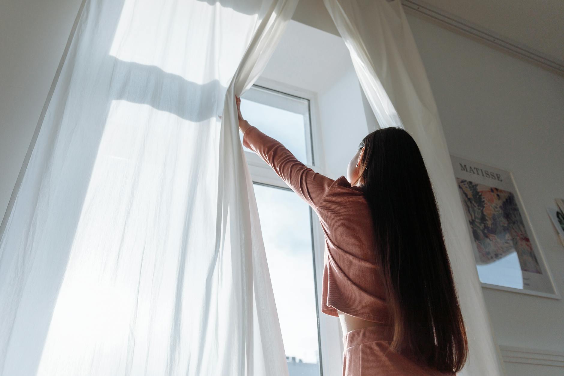 Natural Ventilation Fresh Air Home Woman opening curtains to let in fresh air and natural light for home ventilation