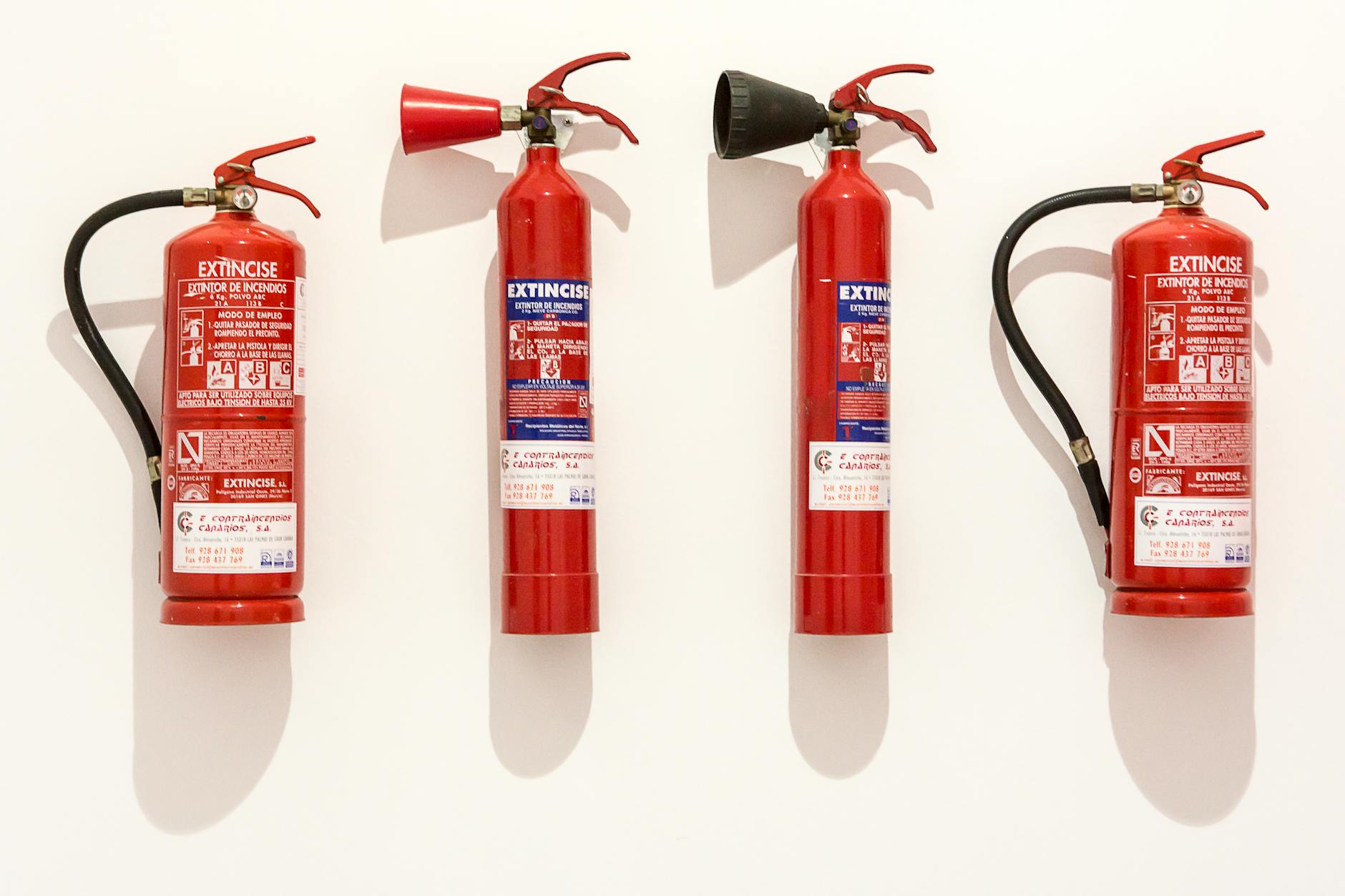 Row of red fire extinguishers mounted on a white wall — essential kitchen fire safety equipment