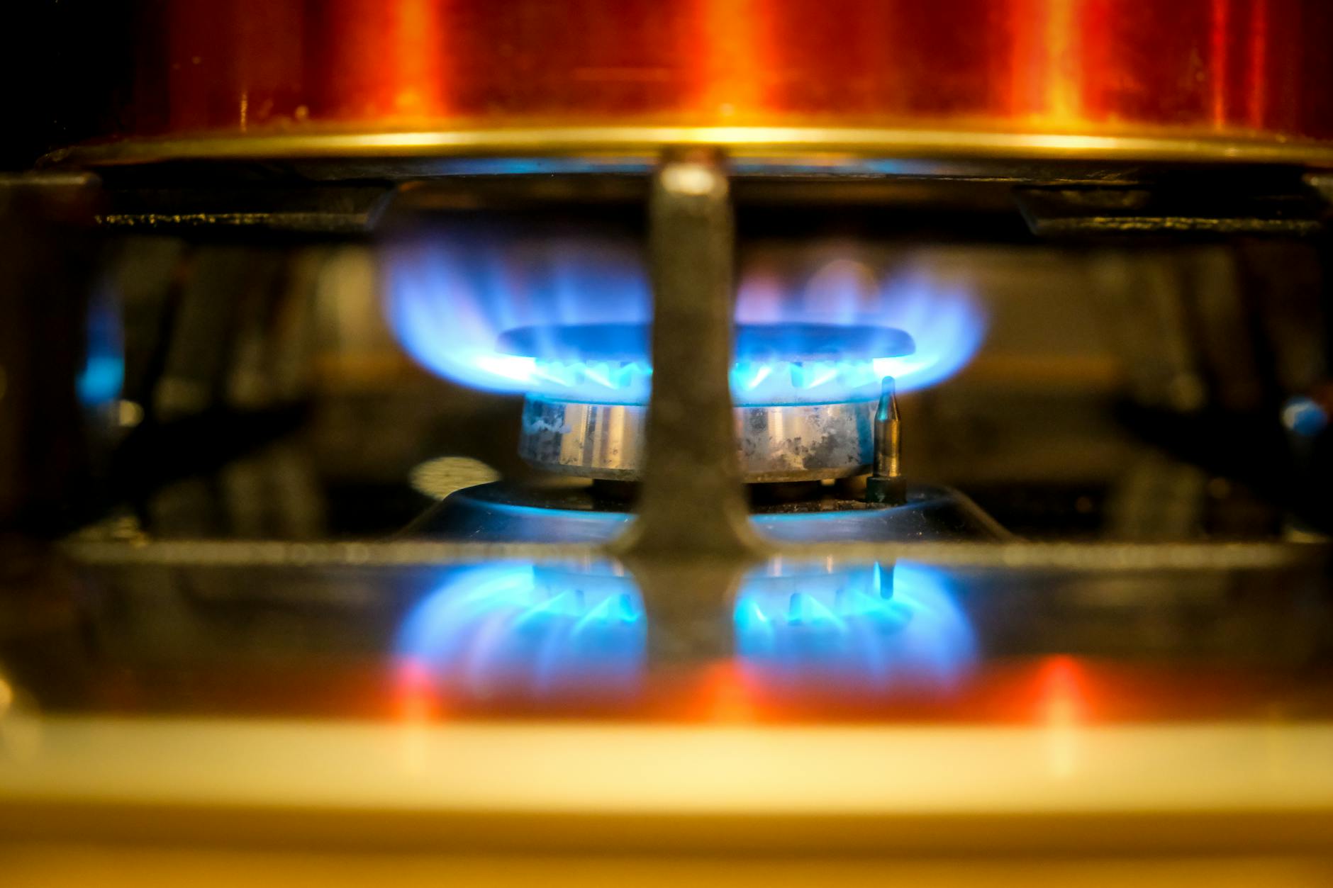 Close-up of a blue gas stove burner flame representing kitchen heat and grease fire risk