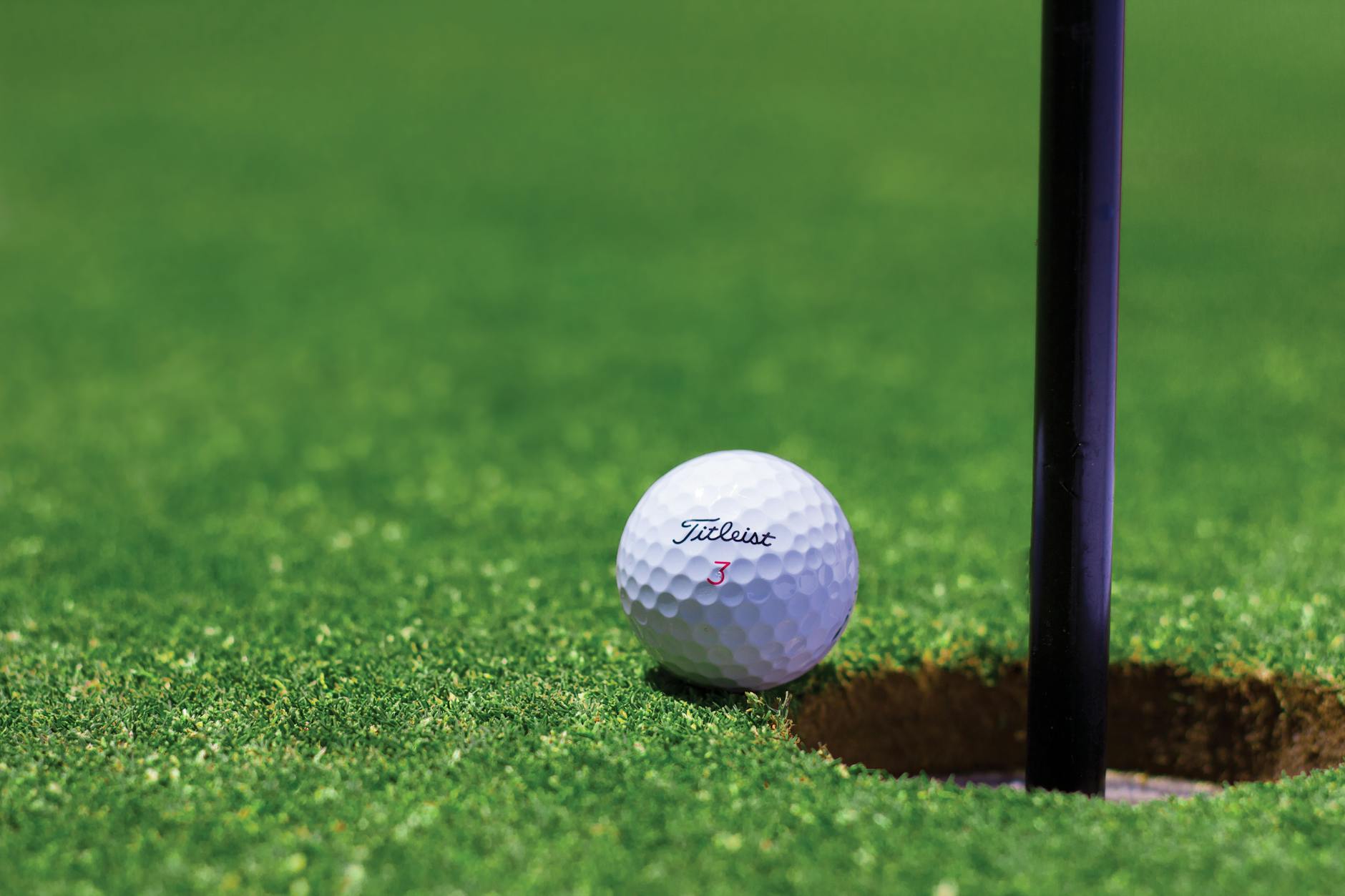 Golf ball resting near the hole on a well-manicured putting green
